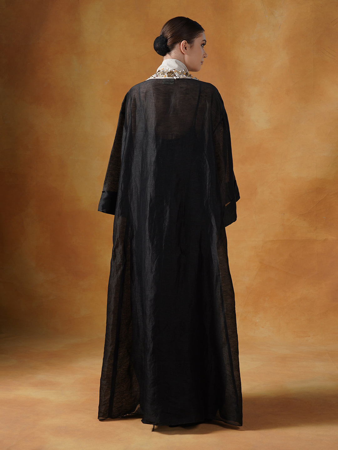 A black floor length lose-fitted gown with an embellished deep yoke neck line.