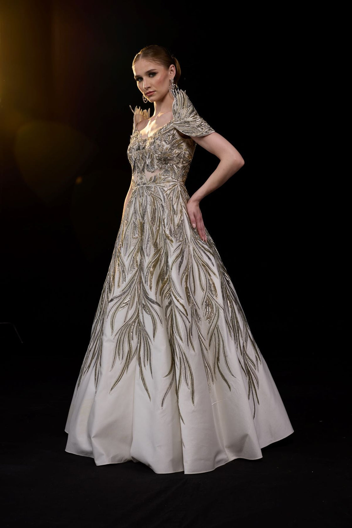 A elegant gown features an off-shoulder design with structured sleeves.