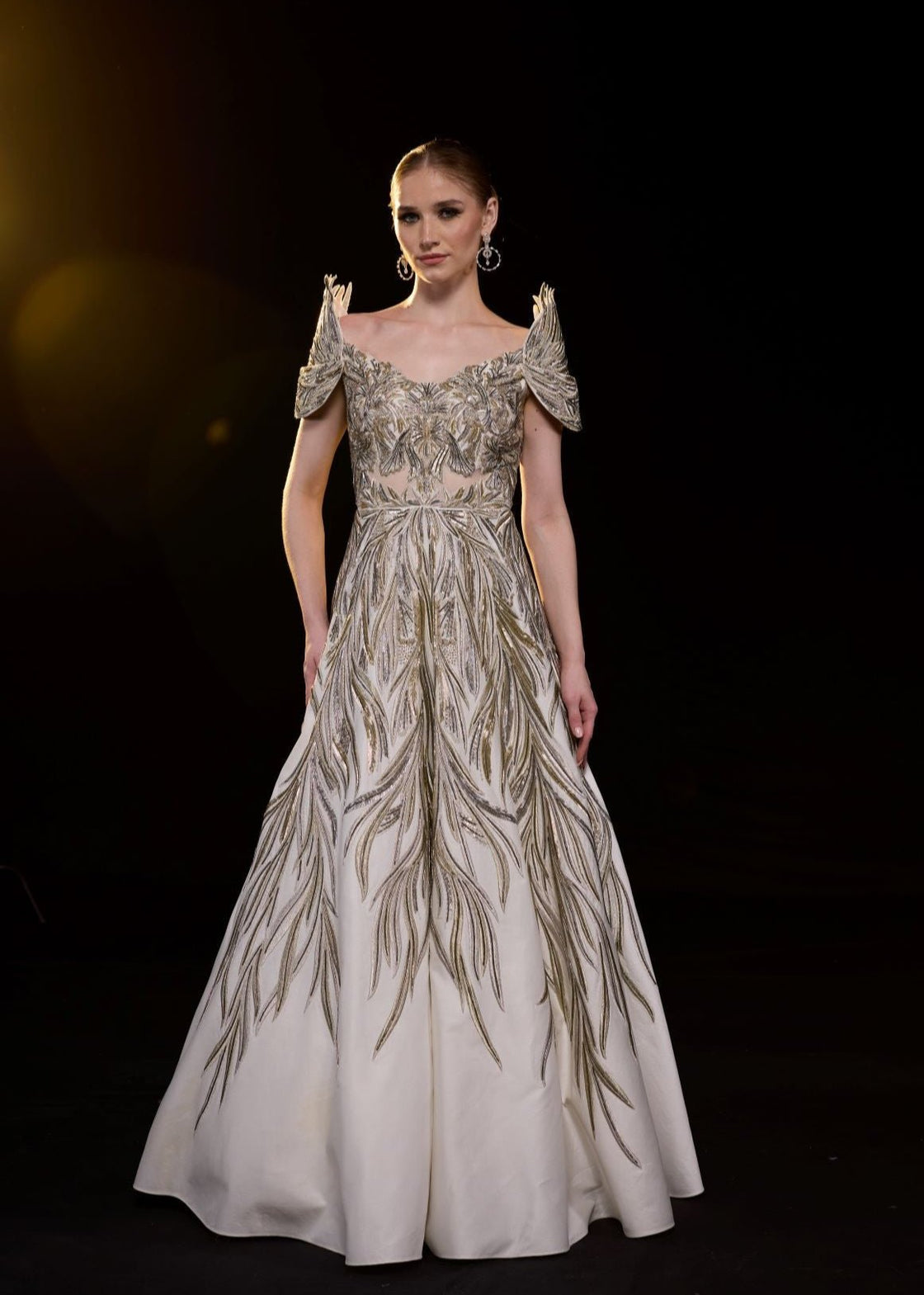 A elegant gown features an off-shoulder design with structured sleeves.