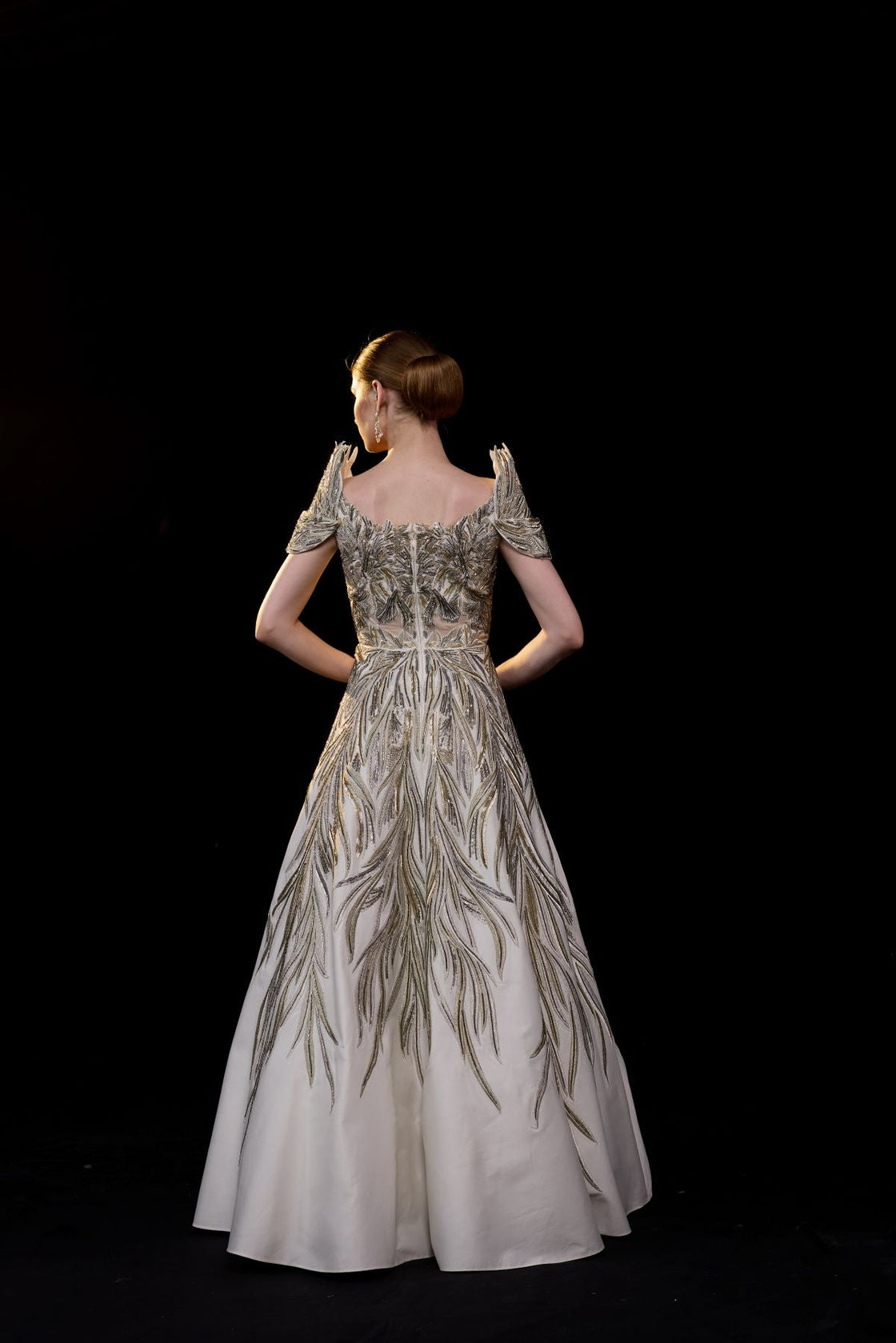 A elegant gown features an off-shoulder design with structured sleeves.