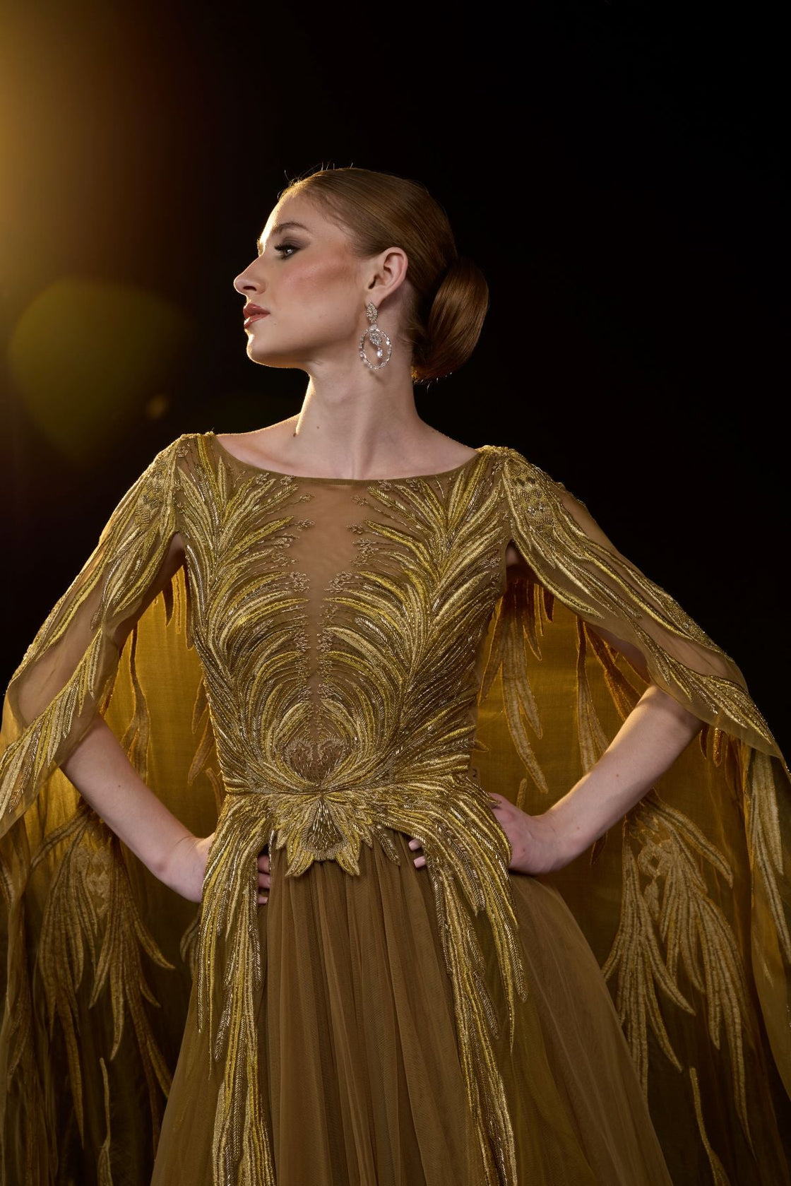 Golden-bronze embroidered gown with elegant, flowing cape sleeves.