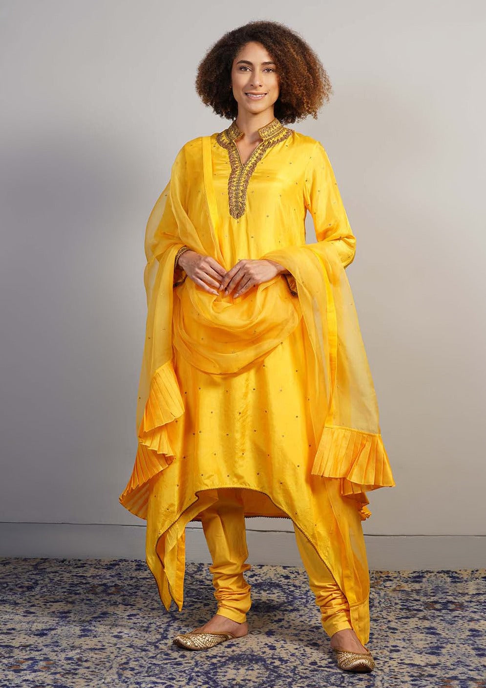 An alluring yellow silk suit set with extended sides is decorated with hand zardosi embroidery