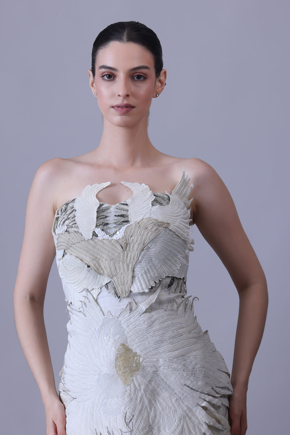 An ethereal strapless gown with layered organza wings in soft ivory and beige tones.