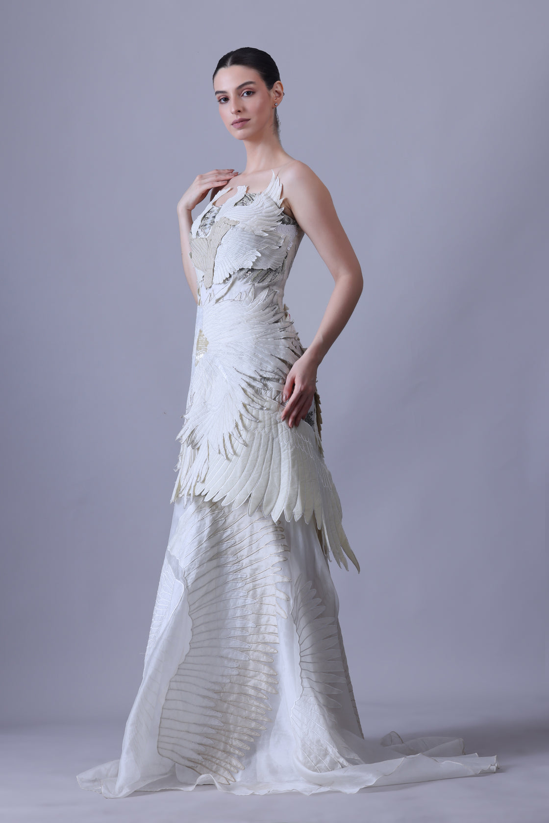 An ethereal strapless gown with layered organza wings in soft ivory and beige tones.