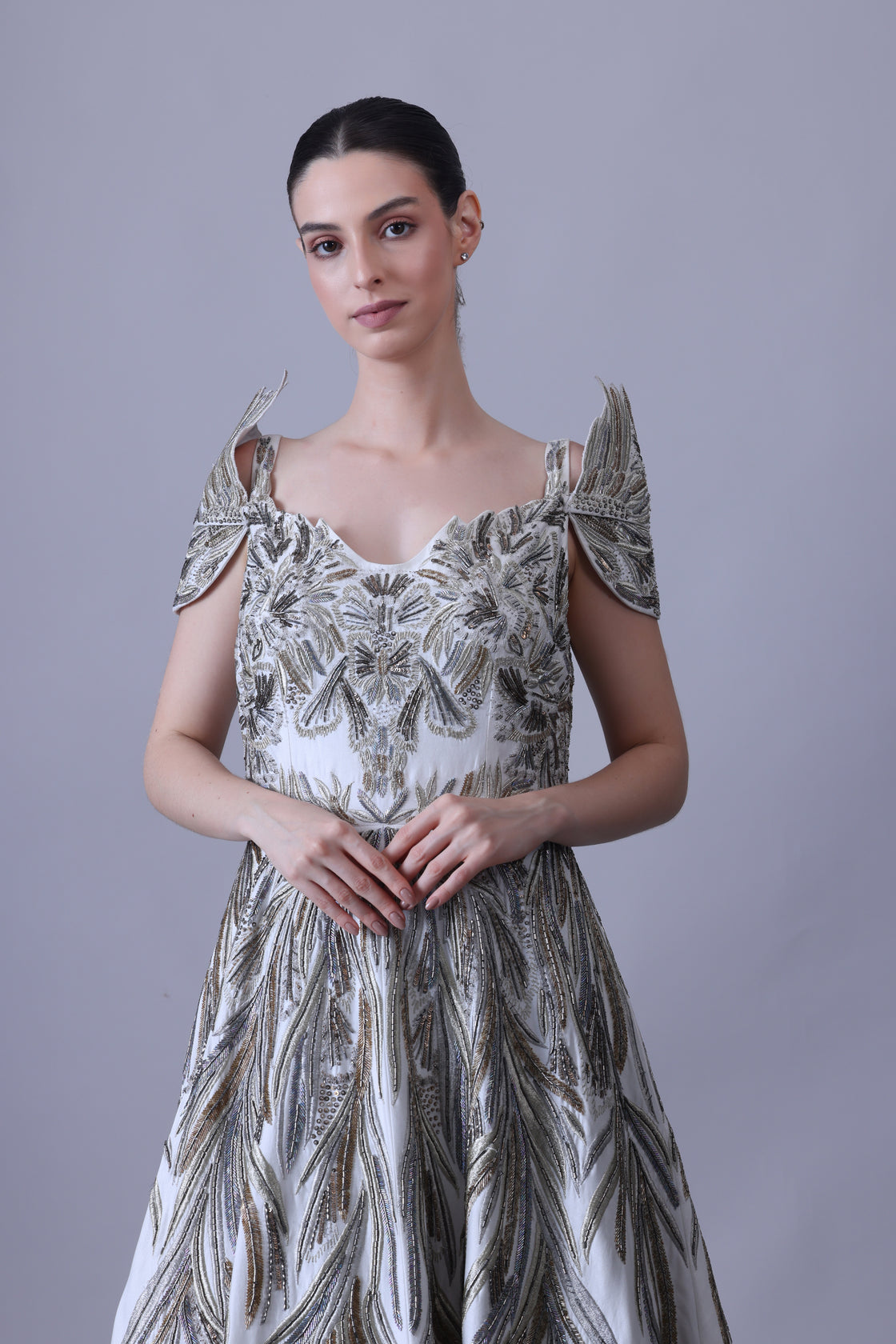 A elegant gown features an off-shoulder design with structured sleeves