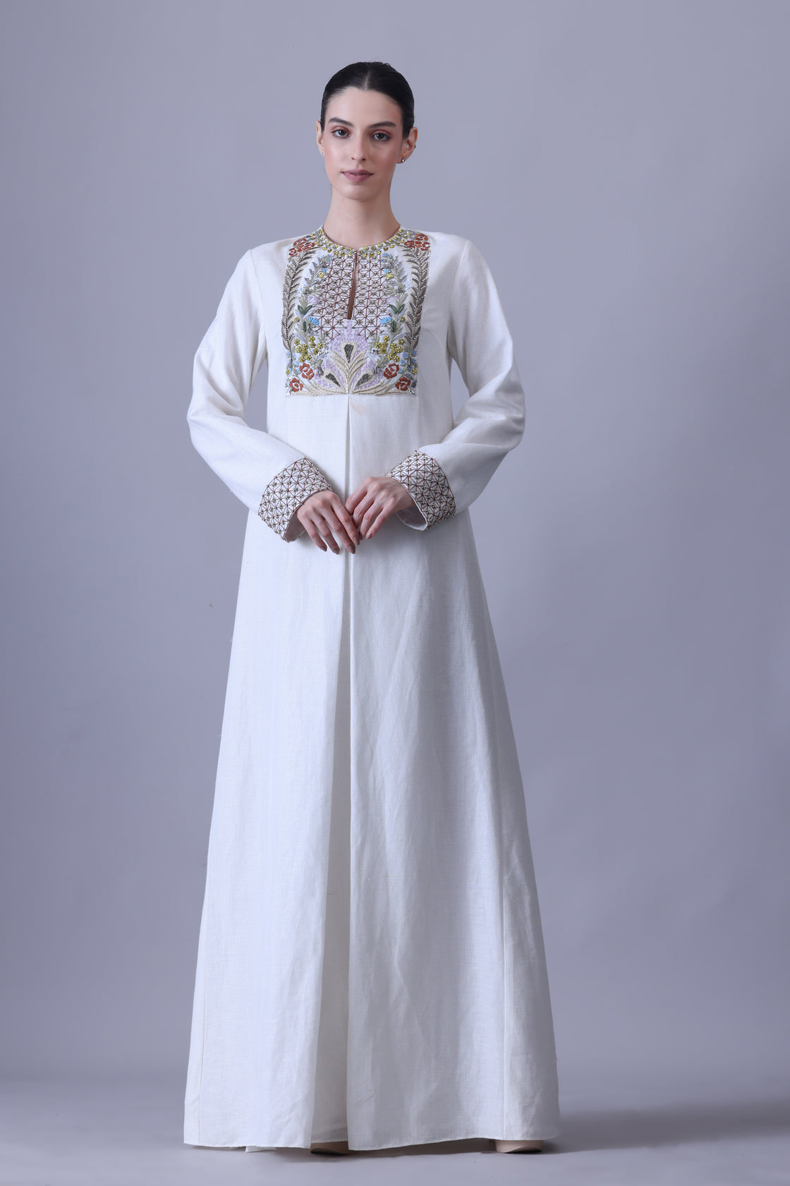 A refined cotton silk jacket paired with a fluid crush cotton skirt, highlighted by vibrant hand embroidery across the bodice that evokes a delicate garden in bloom while maintaining a structured, contemporary elegance.