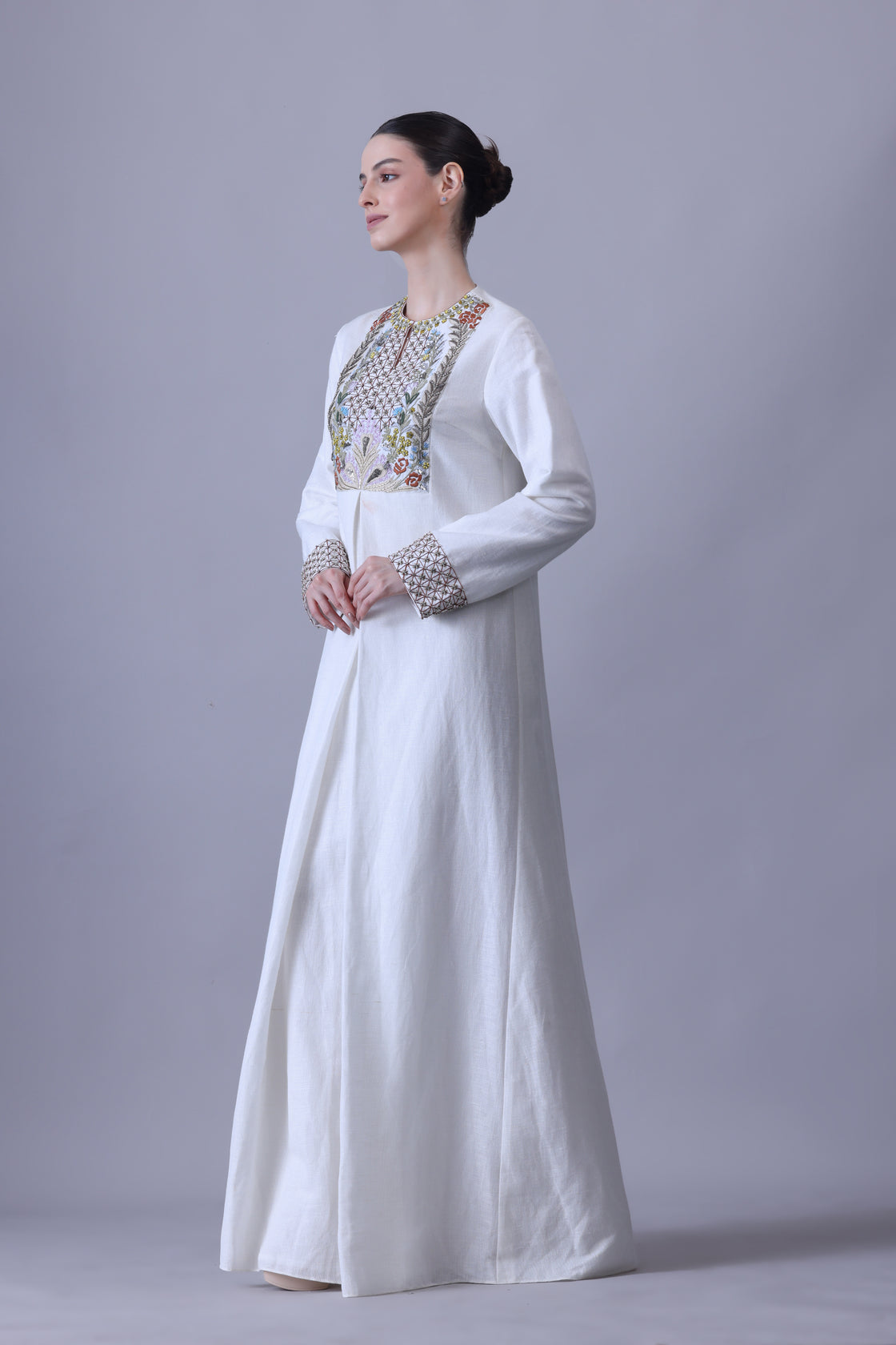 A refined cotton silk jacket paired with a fluid crush cotton skirt, highlighted by vibrant hand embroidery across the bodice that evokes a delicate garden in bloom while maintaining a structured, contemporary elegance.