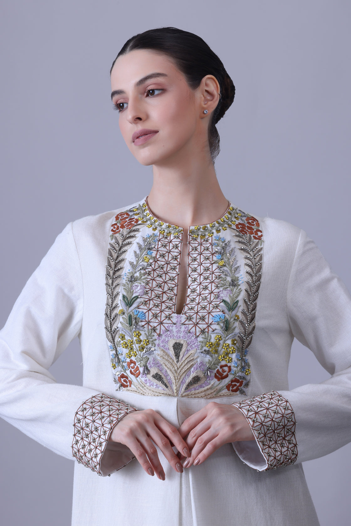 A refined cotton silk jacket paired with a fluid crush cotton skirt, highlighted by vibrant hand embroidery across the bodice that evokes a delicate garden in bloom while maintaining a structured, contemporary elegance.