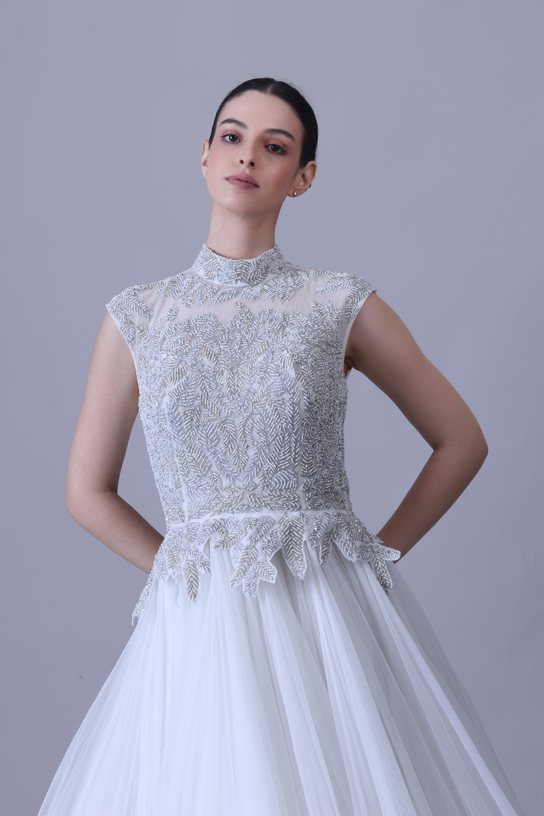 A sleeveless gown features a high-neck embroidered bodice