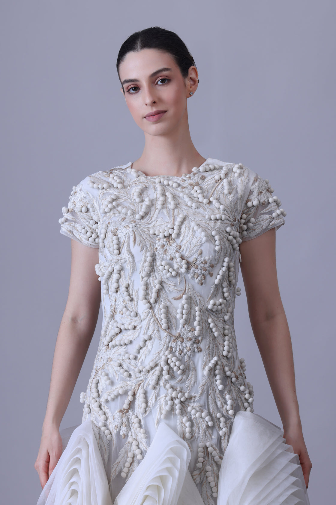A exquisite gown features a sculpted bodice with ornate bead and thread embroidery
