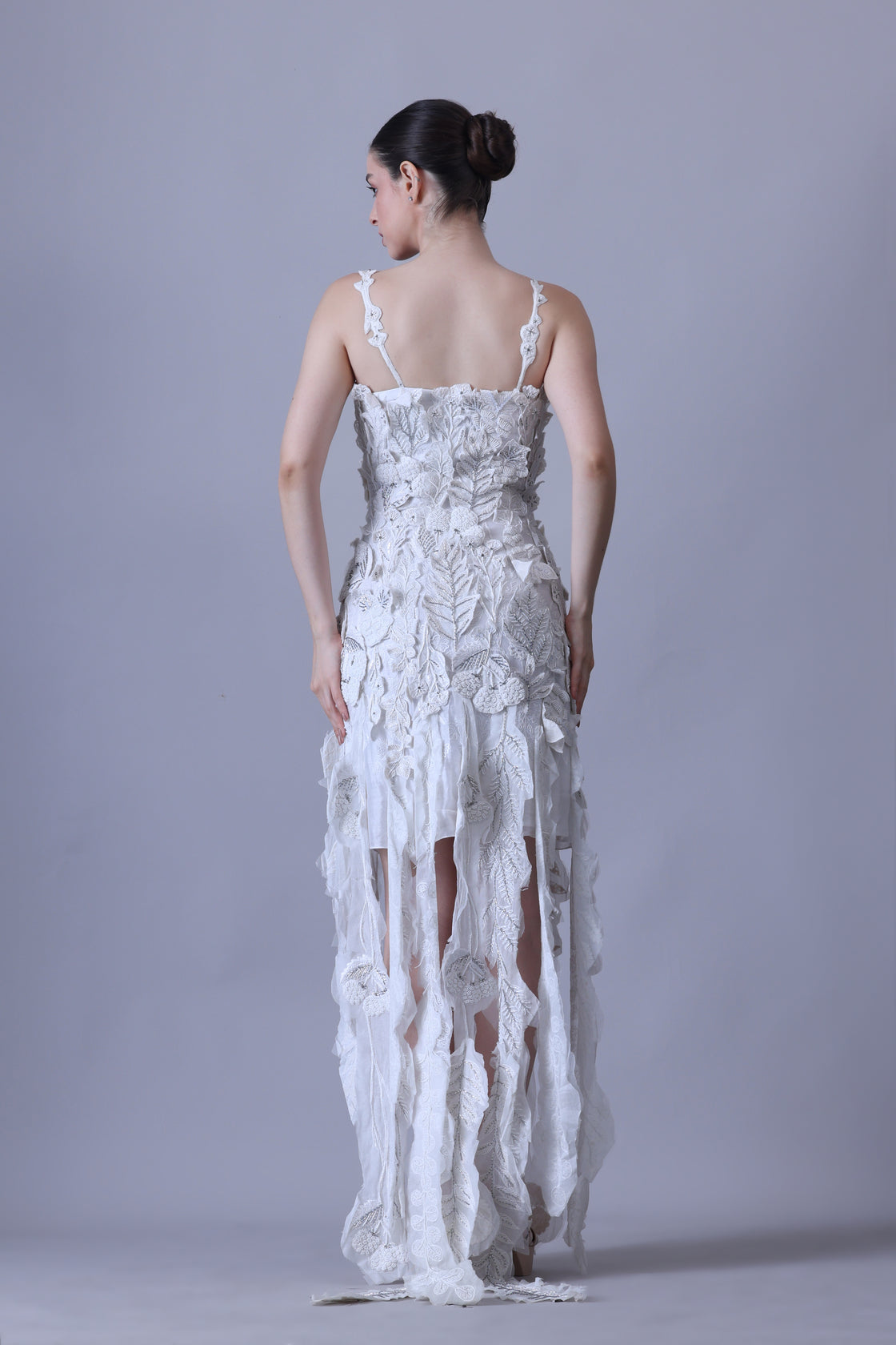 Turn heads in this strappy white gown featuring delicate 3D floral appliqués