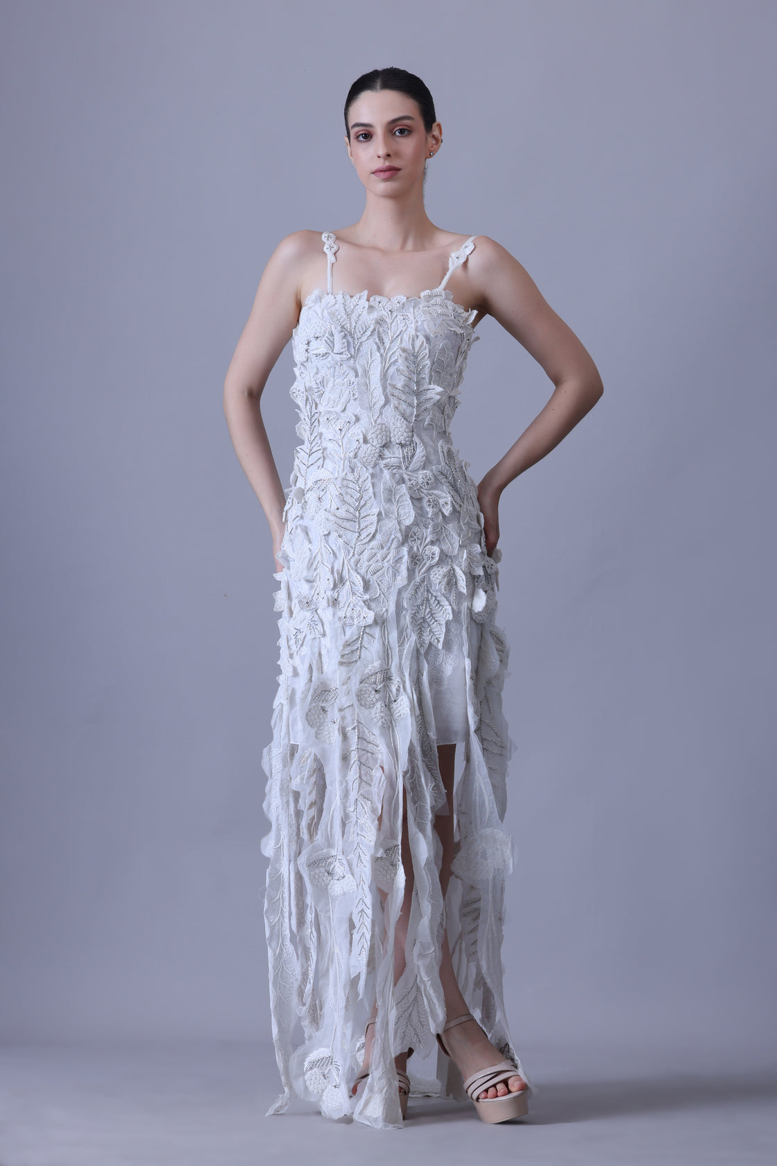 Turn heads in this strappy white gown featuring delicate 3D floral appliqués
