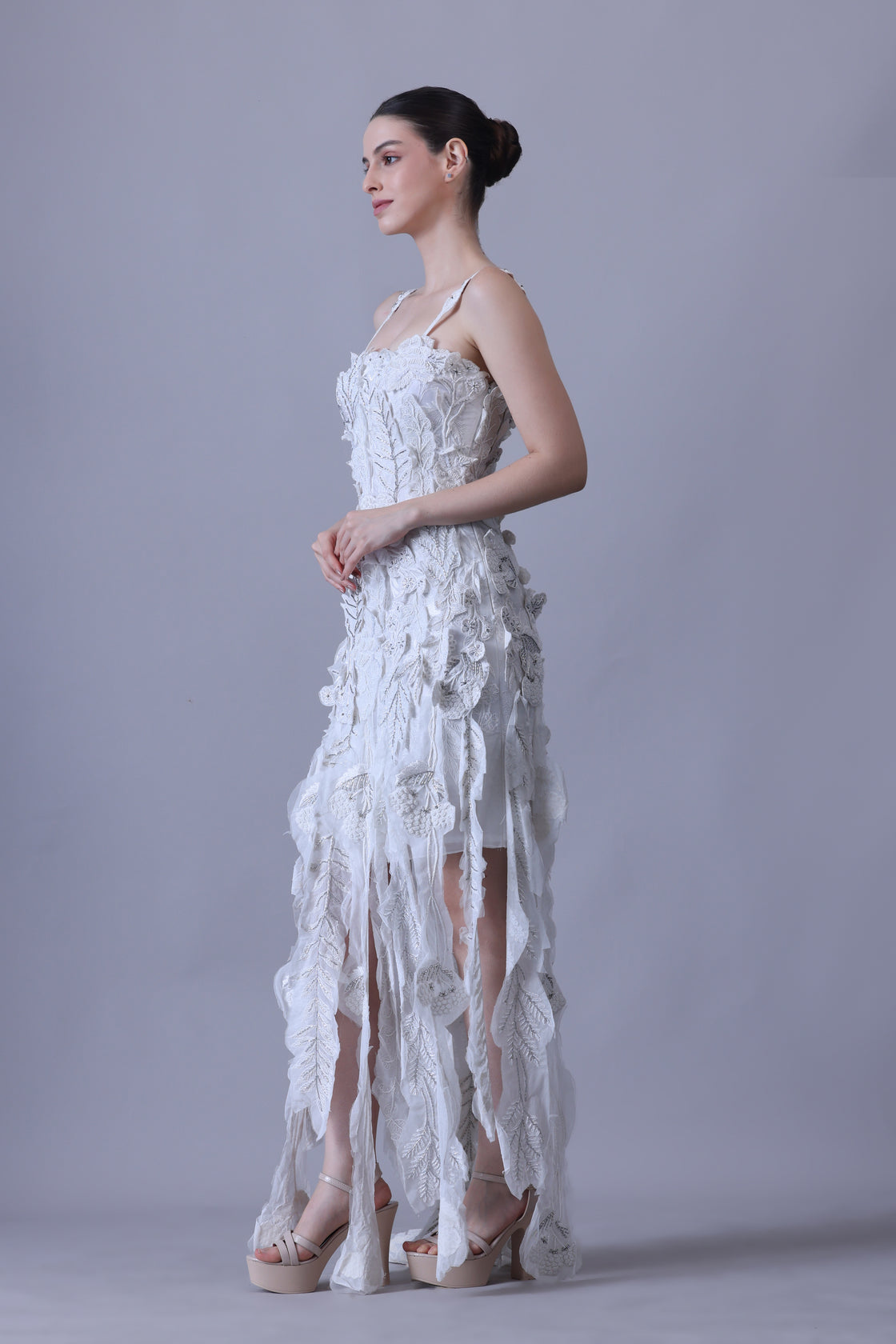 Turn heads in this strappy white gown featuring delicate 3D floral appliqués