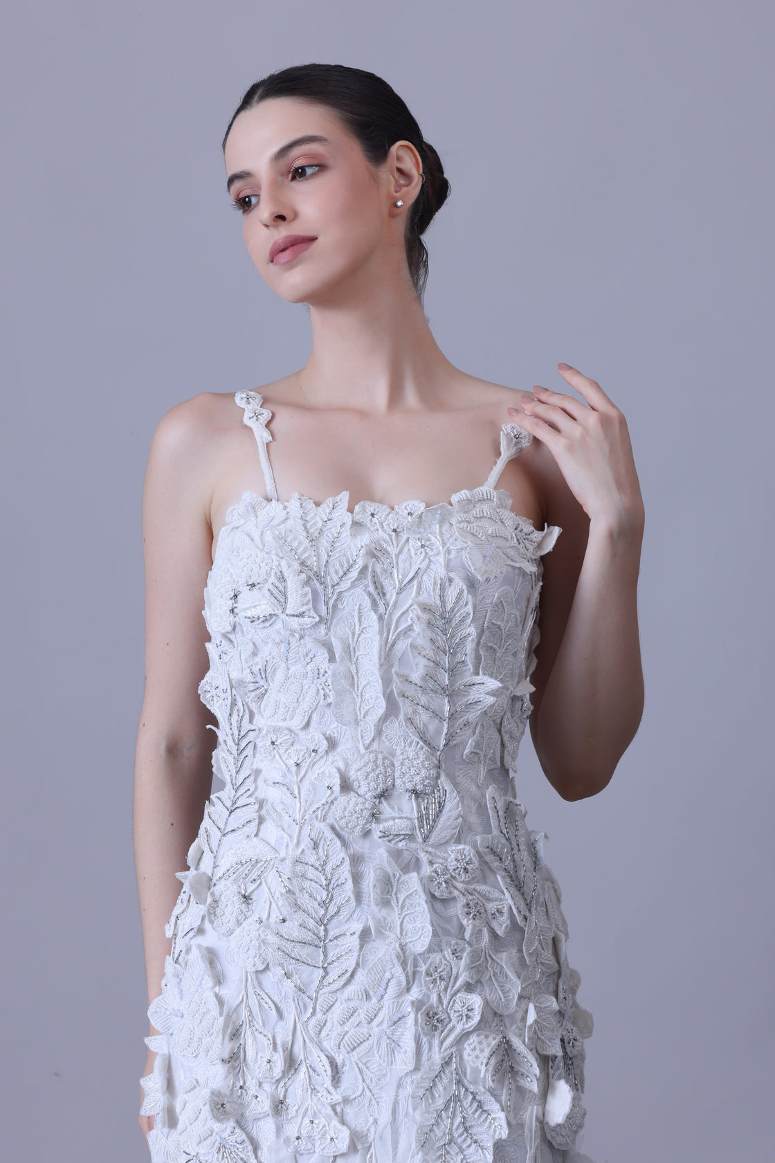 Turn heads in this strappy white gown featuring delicate 3D floral appliqués