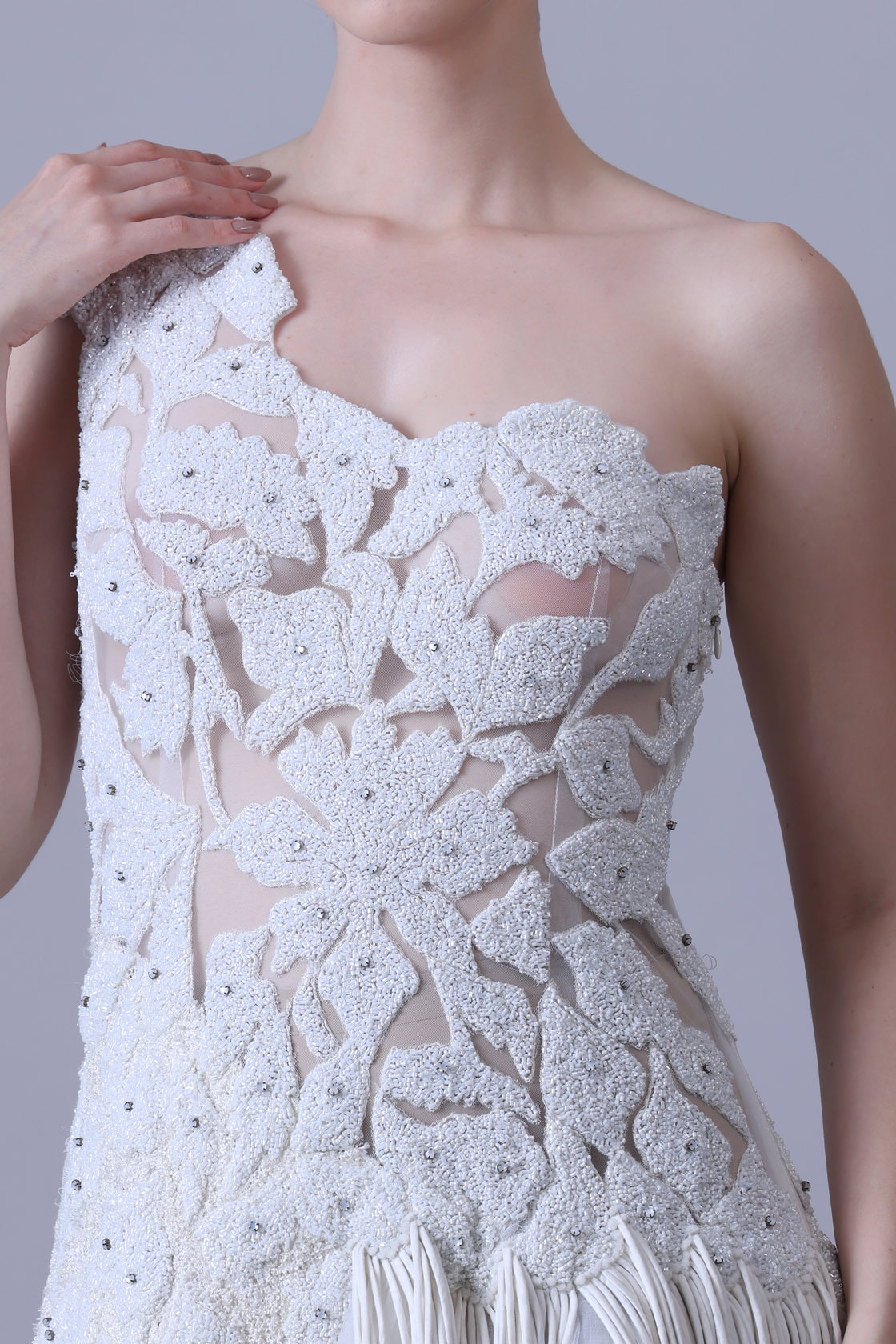 Ivory one-shoulder gown with sheer accents and floral appliqué.