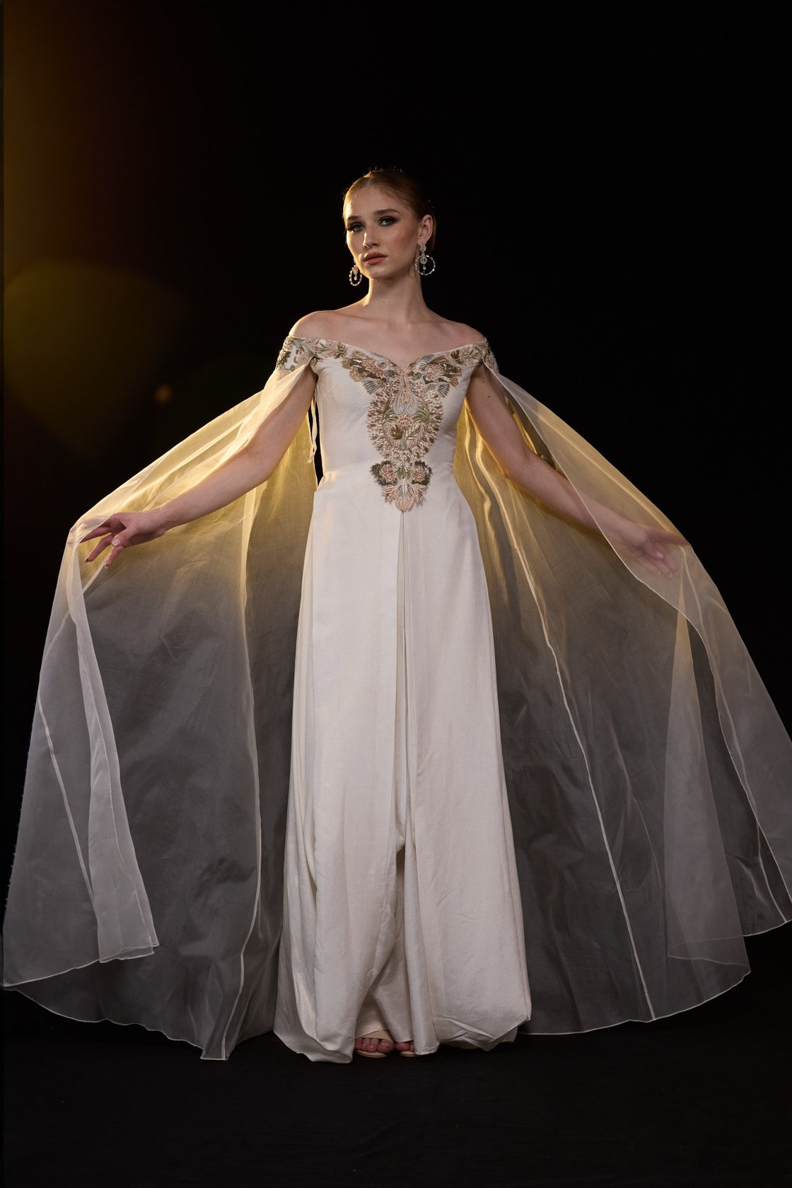 Ivory Off-Shoulder Gown With Floral Embroidery, Sheer Cape Sleeves And A Fluid Floor Length Silhouette