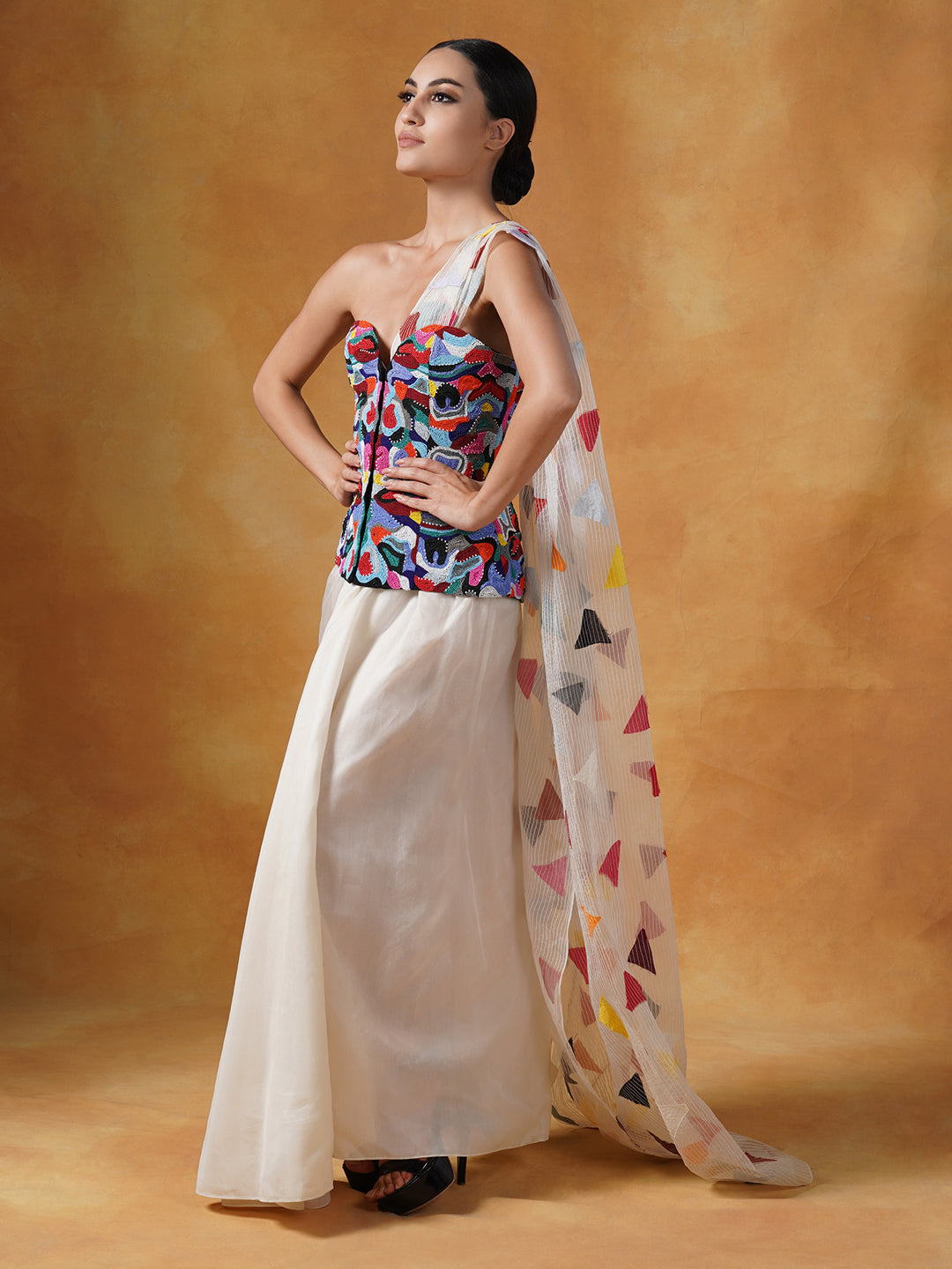 Corset that is intricately embroidered in colorful beads, decorated with a printed pallu and is paired with a plain white cotton silk drape skirt.