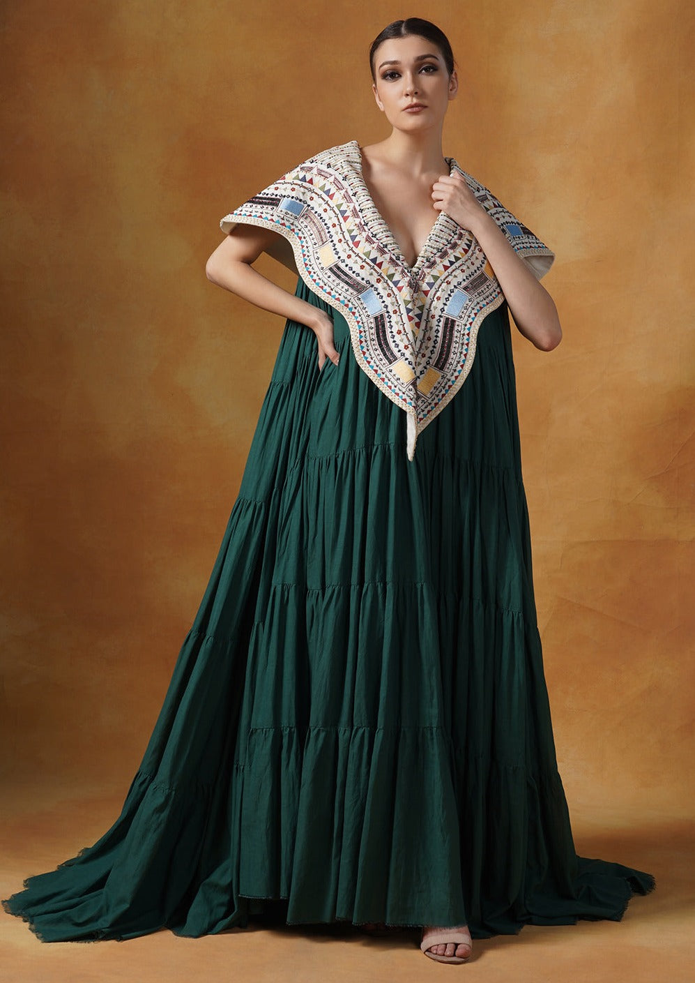 Floor length cotton tier dress in olive green. It is topped with a heavy embroidered cape around the neckline and shoulders.