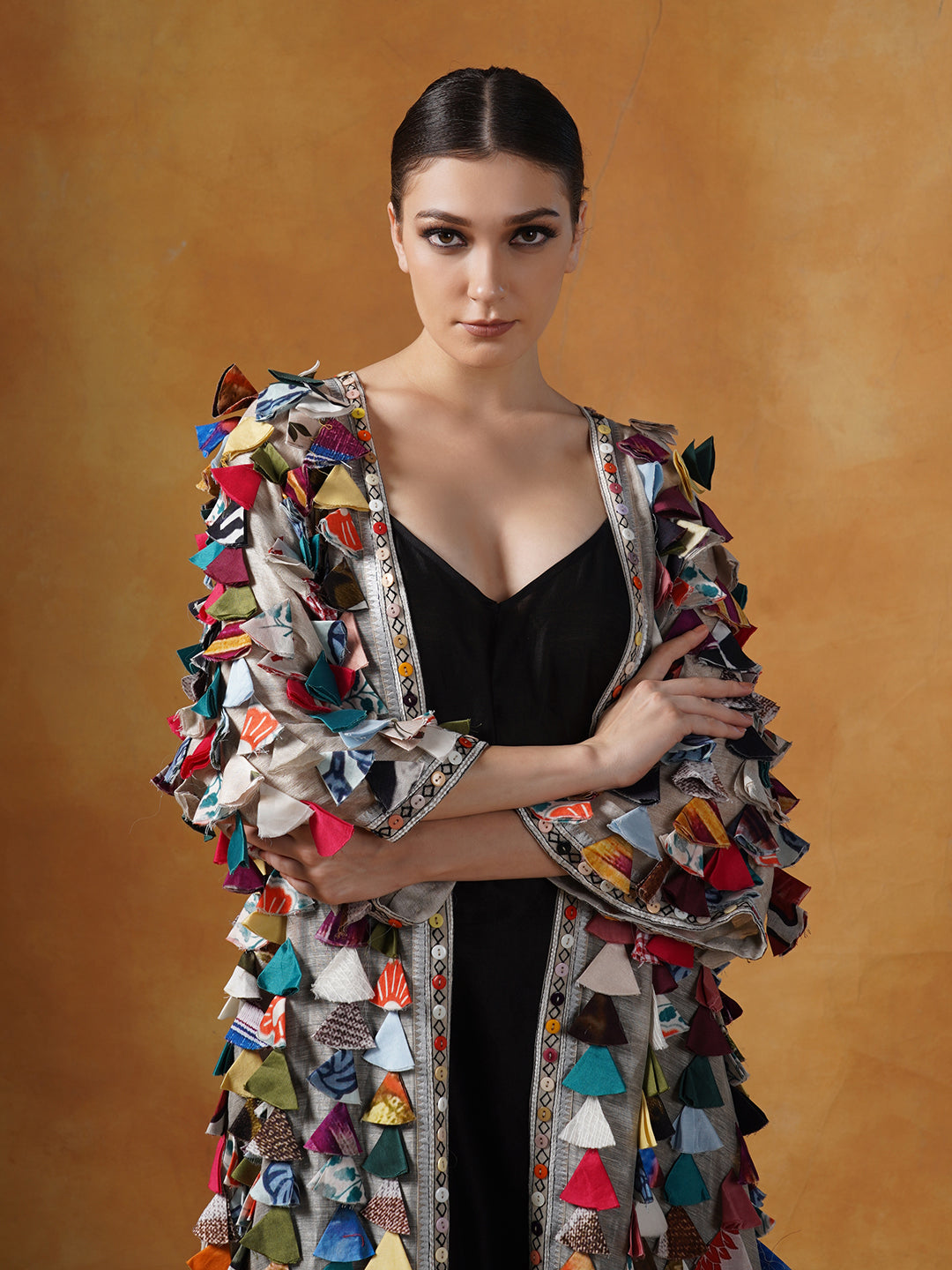 A black cotton silk slip is topped with a cotton silk jacket with colorful tassel art.
