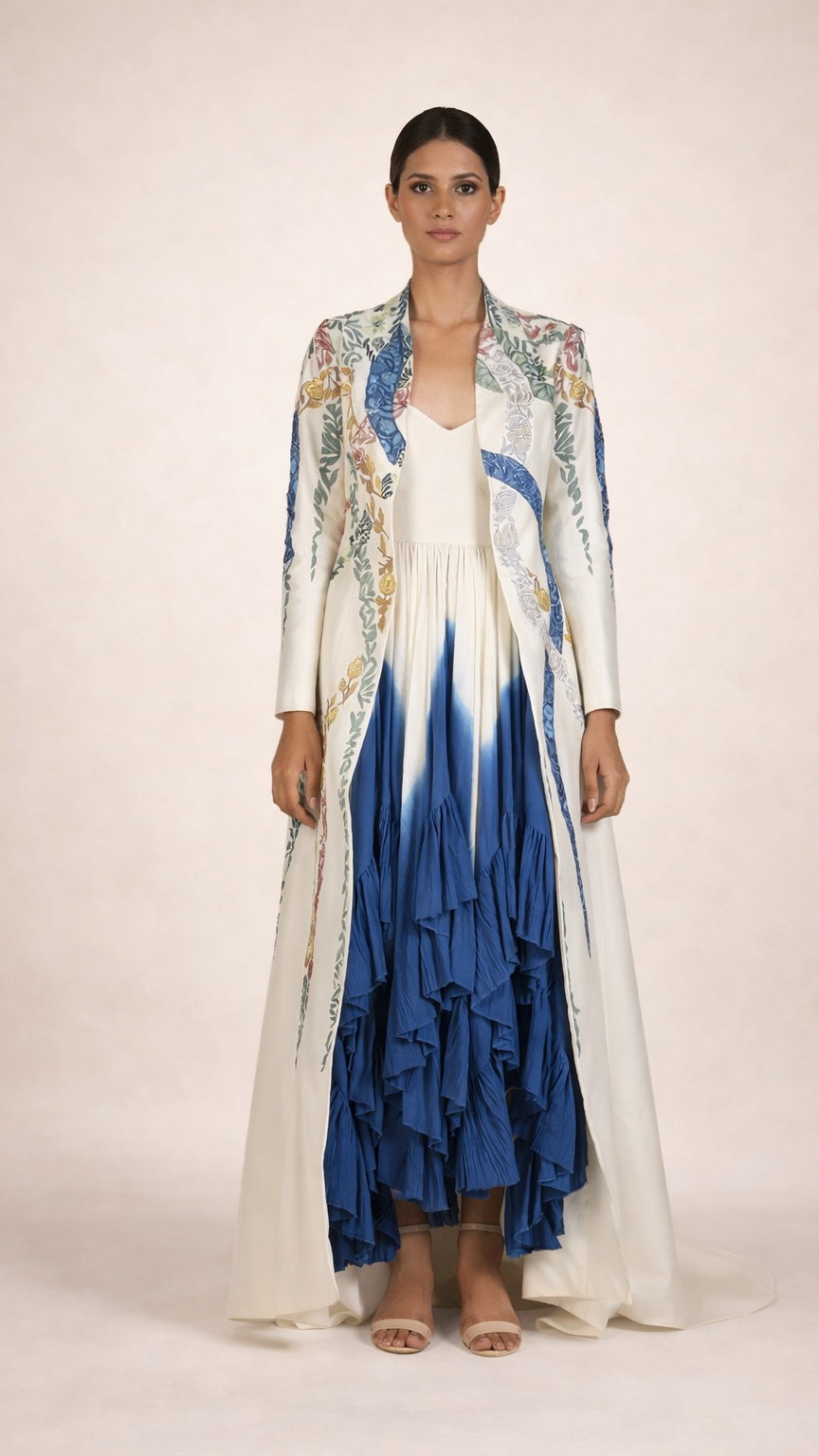 Woman wearing a long, colorful dress with a floral pattern on a plain background