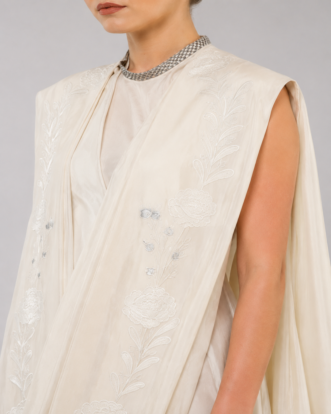 Ivory embroidered draped ensemble featuring floral threadwork, a fluid cowl silhouette, and contemporary cape-inspired styling