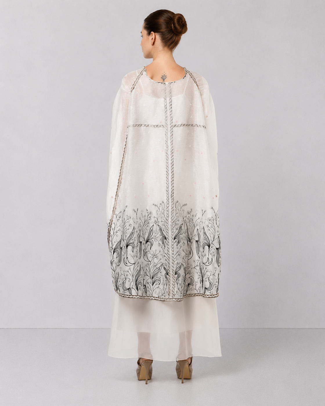 Ivory embroidered cape dress with sheer layering and floral motifs.