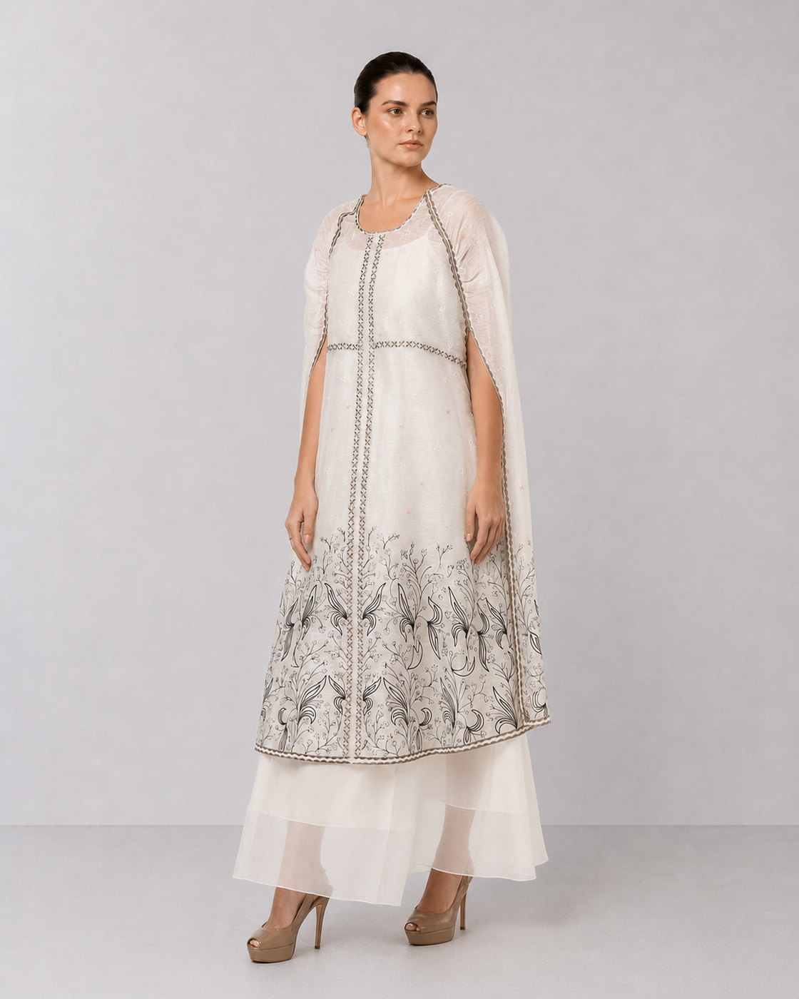 Ivory embroidered cape dress with sheer layering and floral motifs.