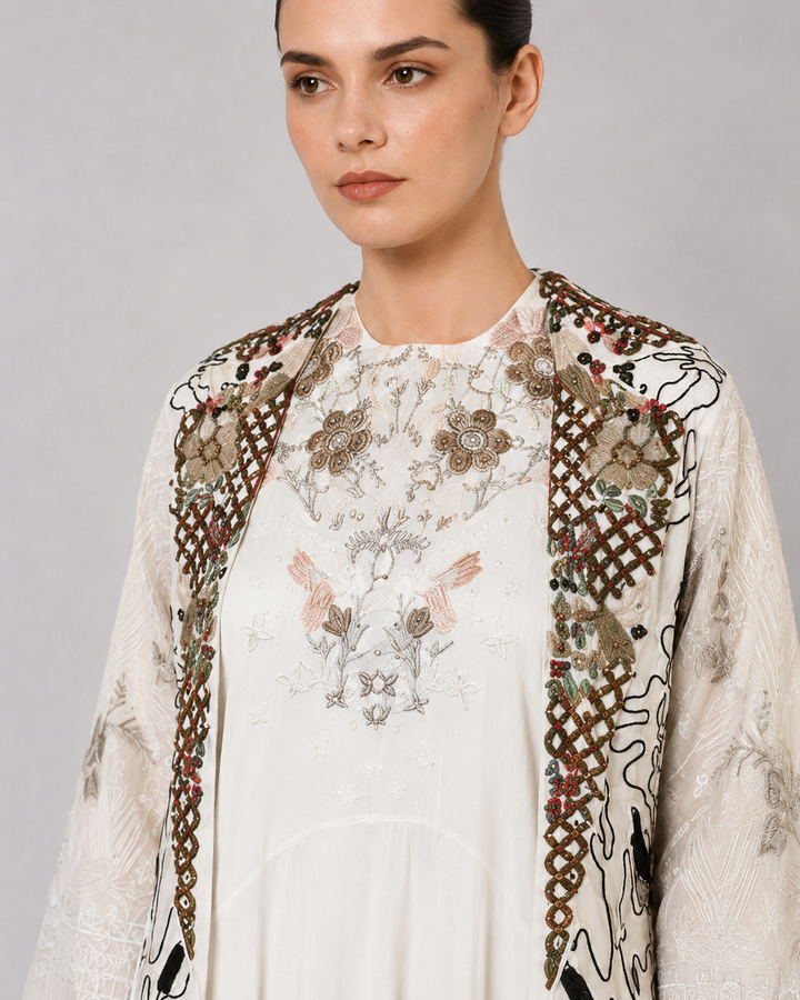 Ivory layered dress with embroidered artwork and statement overcoat.