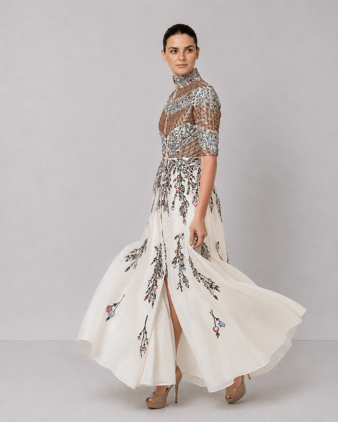Ivory embroidered gown with structured high neck and cascading floral motifs.