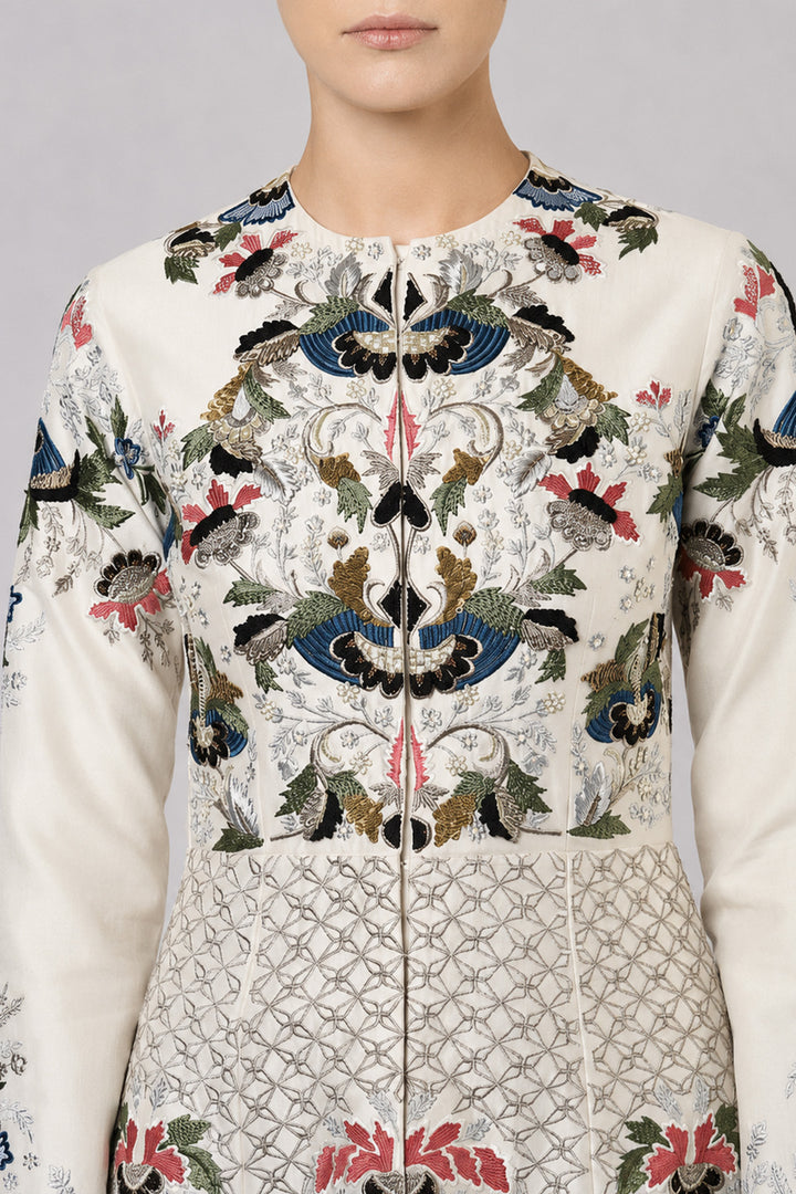 Ivory embroidered gown with artisanal floral motifs and flared silhouette.