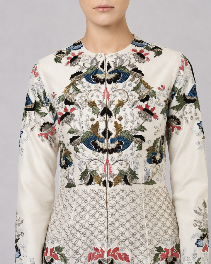Ivory embroidered gown with artisanal floral motifs and flared silhouette.