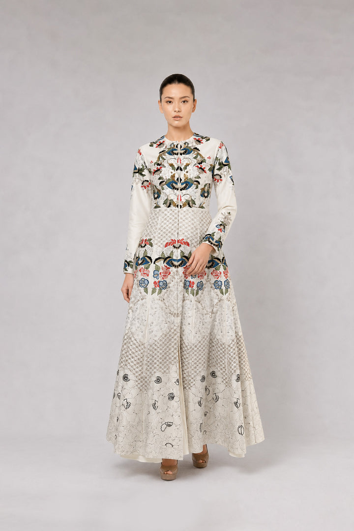 Ivory embroidered gown with artisanal floral motifs and flared silhouette.