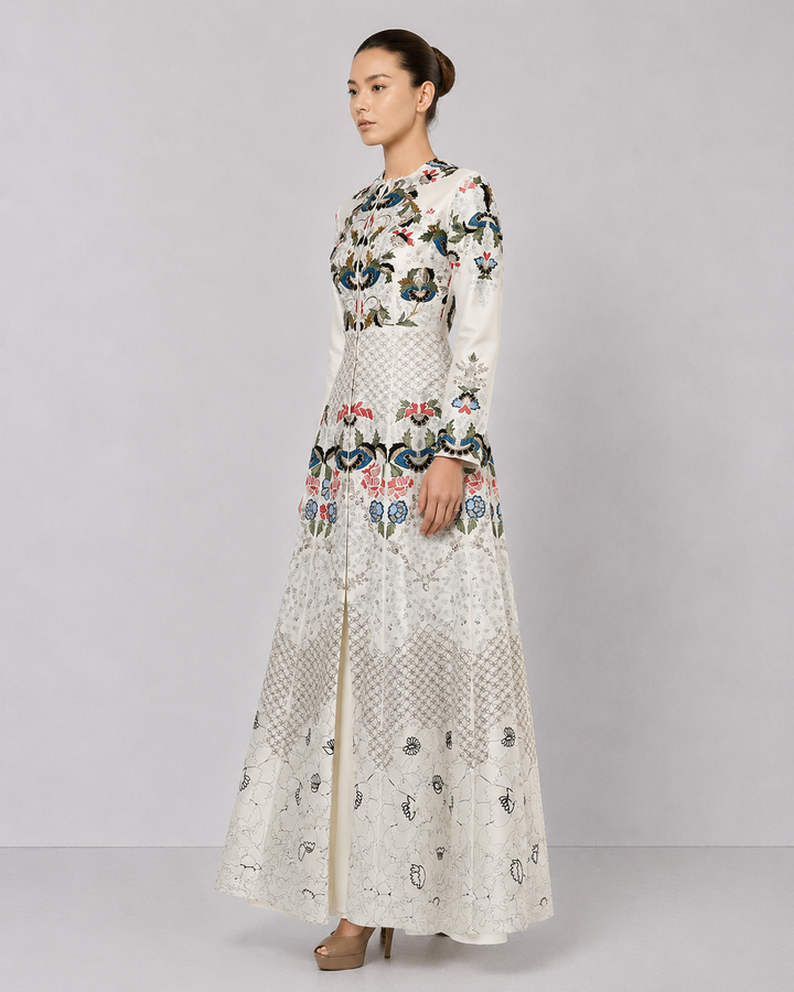 Ivory embroidered gown with artisanal floral motifs and flared silhouette.