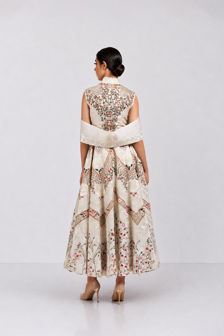 Ivory embroidered dress with sculpted cape collar and botanical motifs.