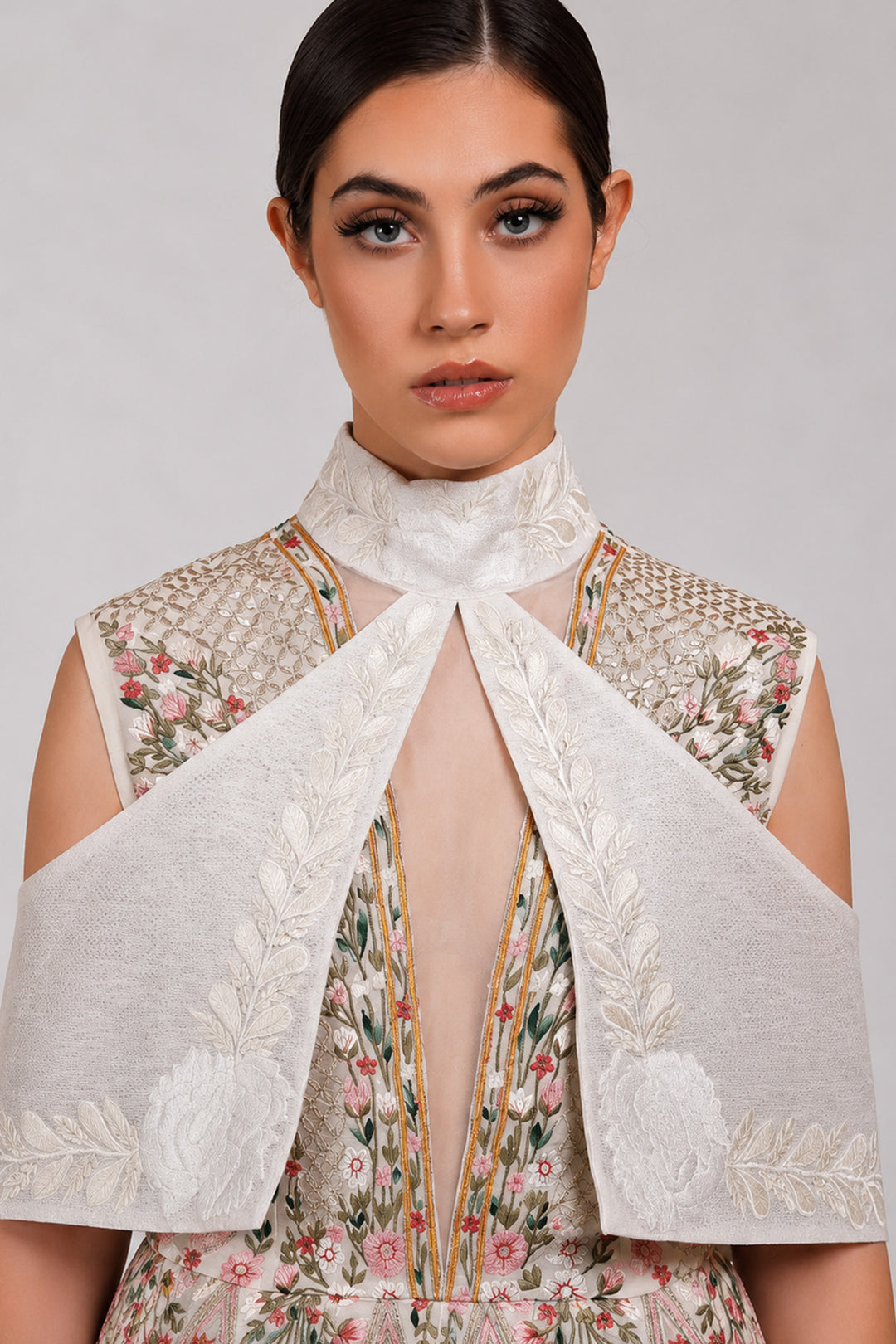 Ivory embroidered dress with sculpted cape collar and botanical motifs.
