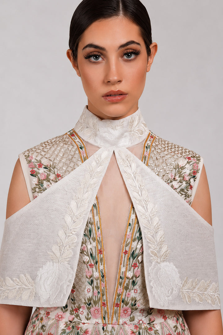 Ivory embroidered dress with sculpted cape collar and botanical motifs.