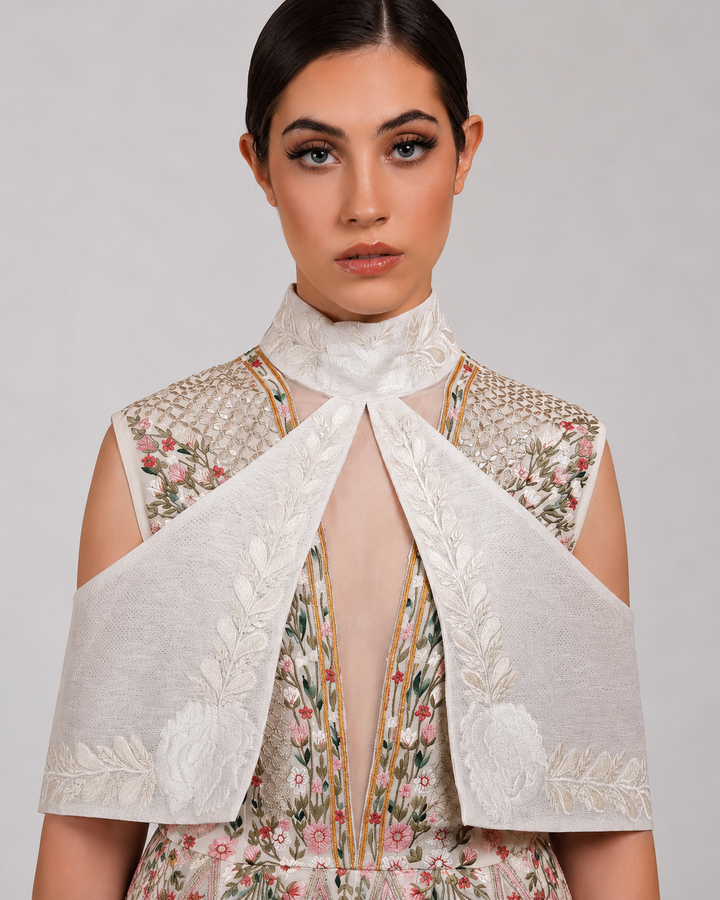 Ivory embroidered dress with sculpted cape collar and botanical motifs.
