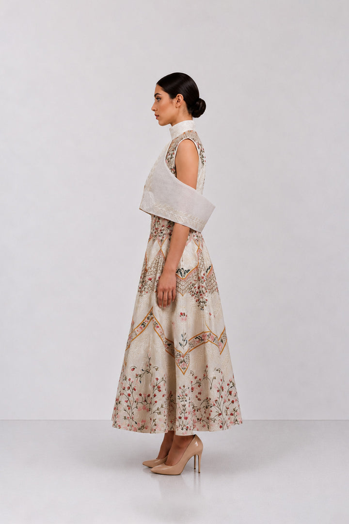 Ivory embroidered dress with sculpted cape collar and botanical motifs.