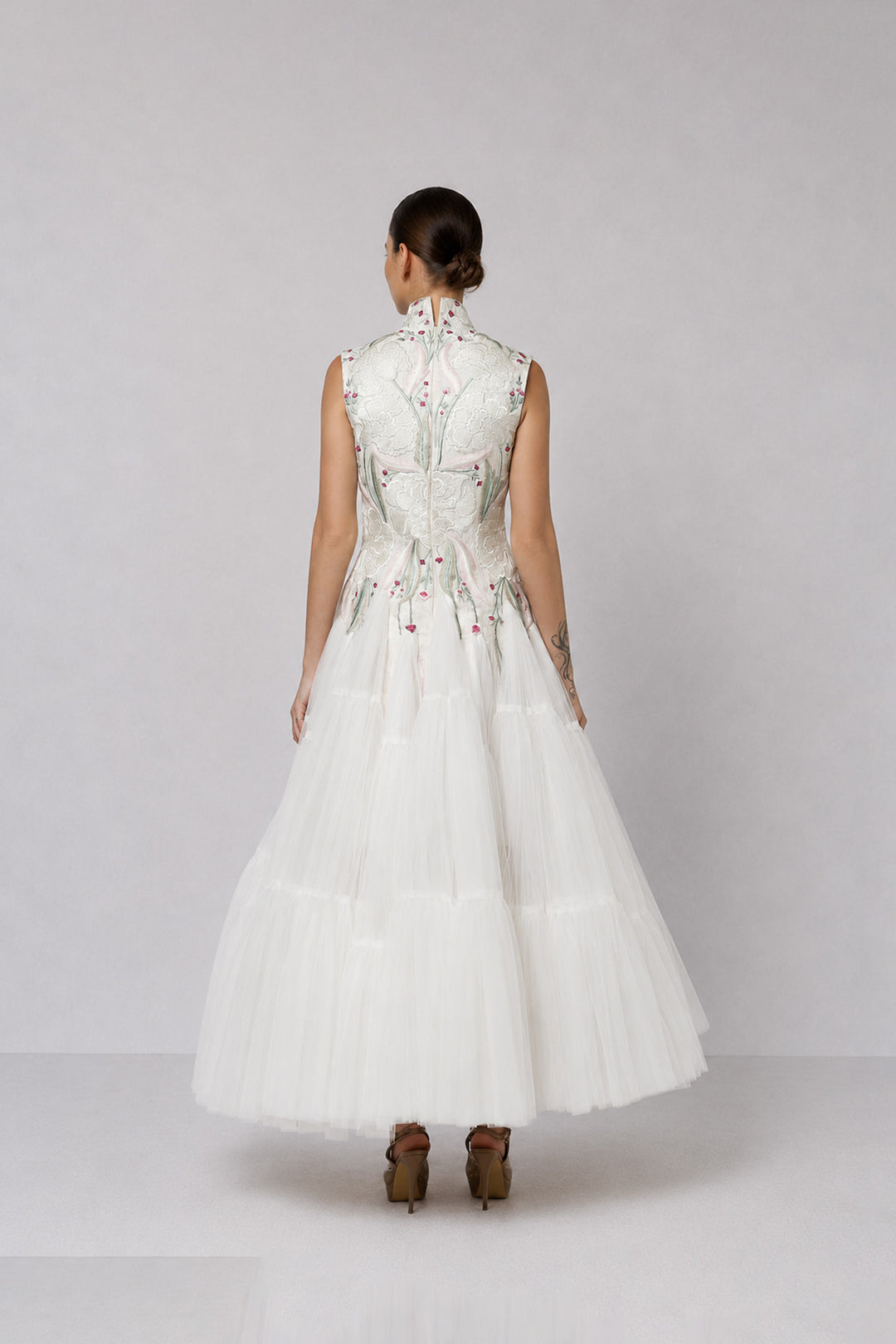 Ivory tiered tulle gown with embroidered bodice and high-neck detailing.