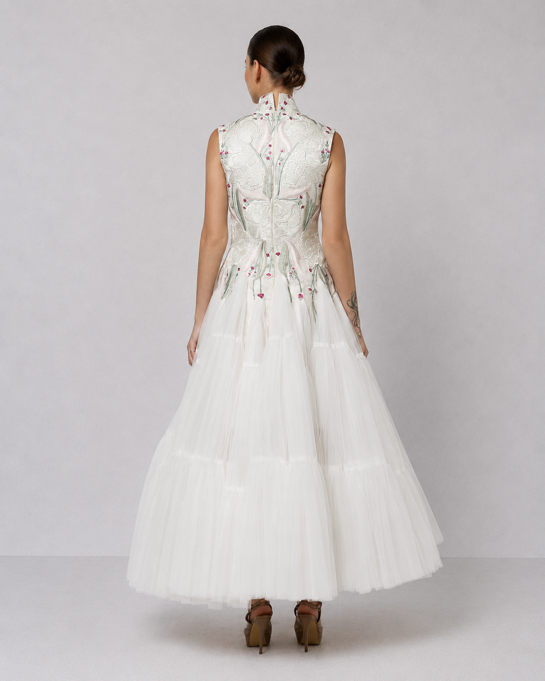 Ivory tiered tulle gown with embroidered bodice and high-neck detailing.