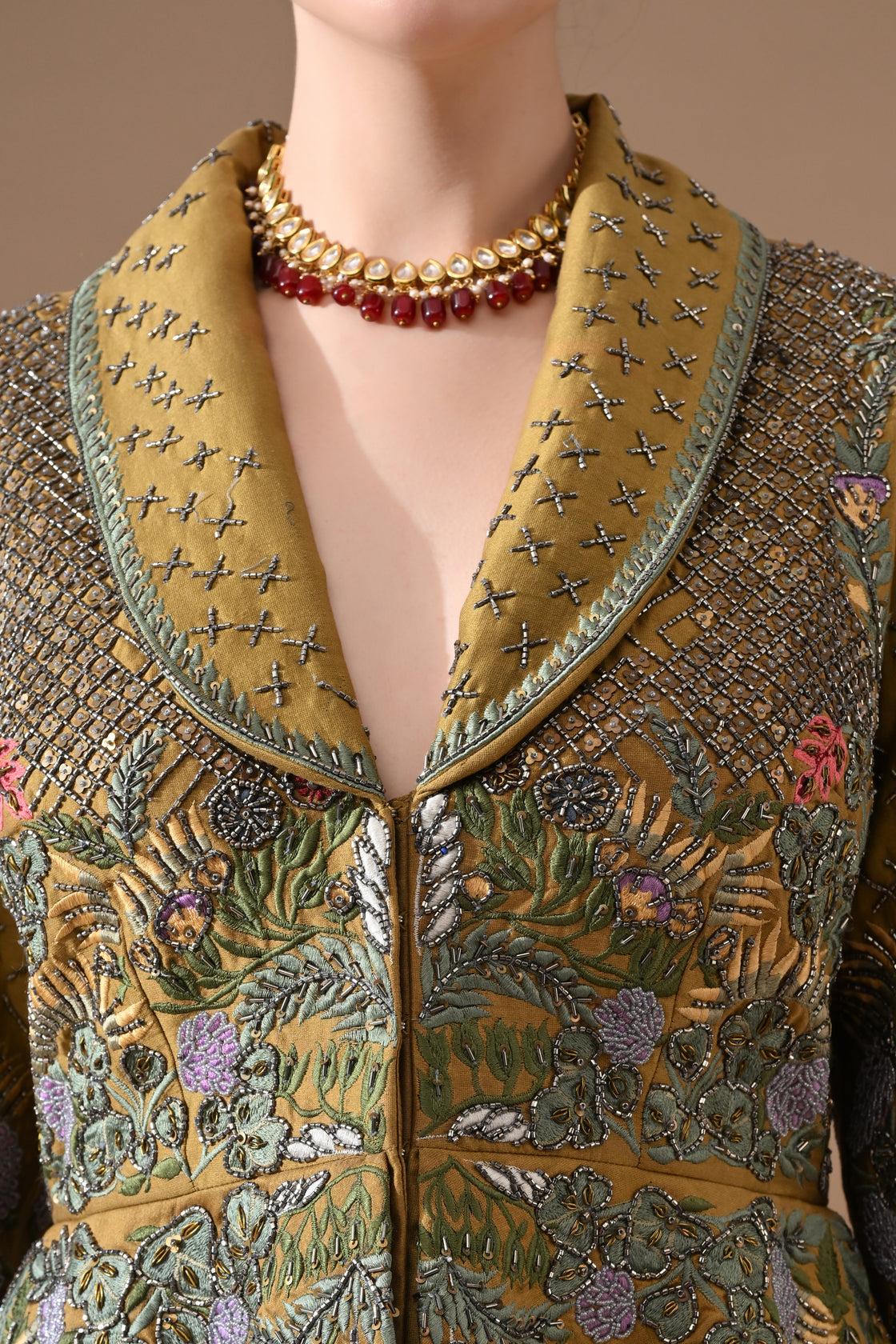 A olive green jacket features intricate all-over embroidery with skirt