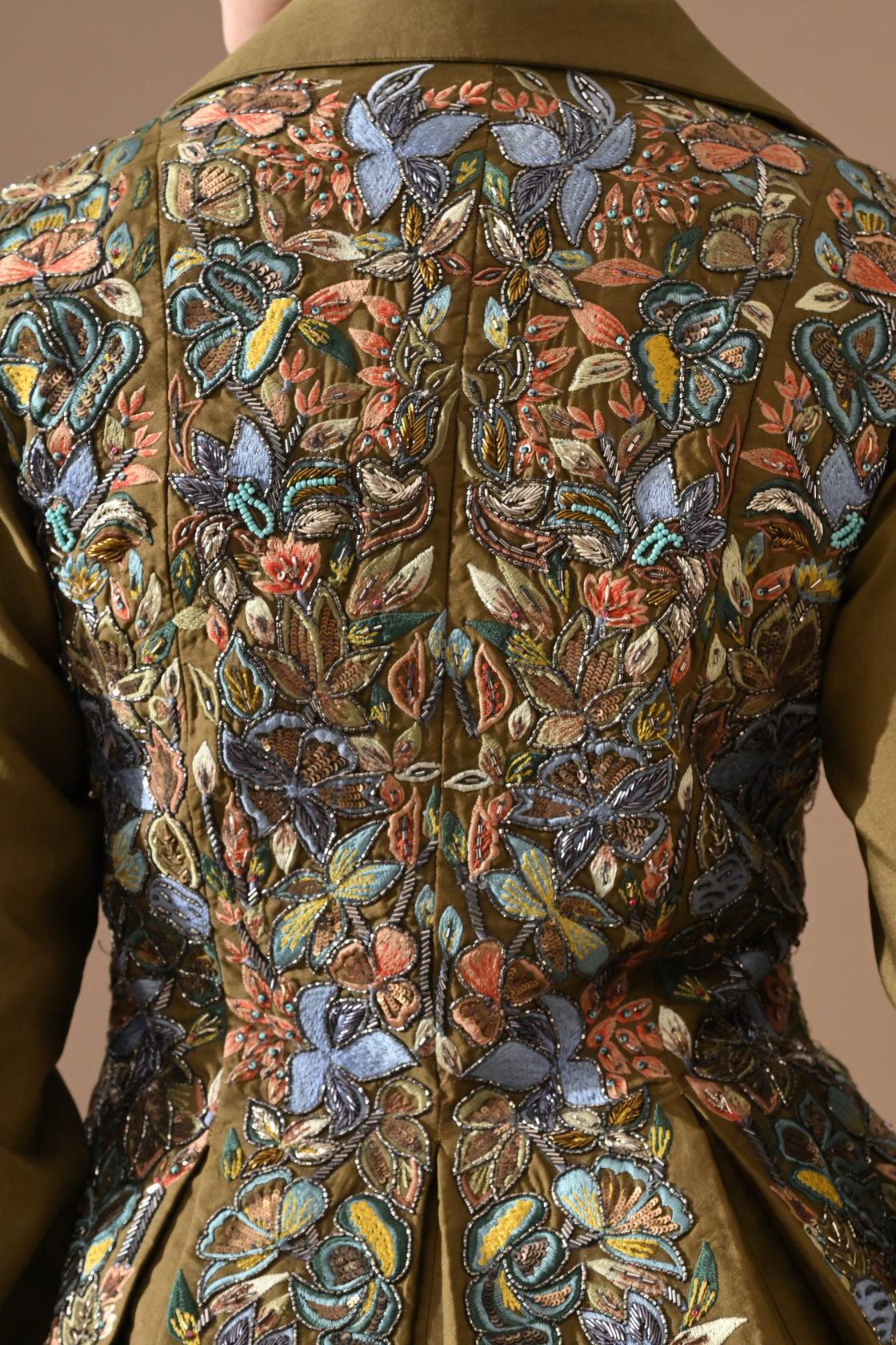 A olive green jacket features intricate all-over embroidery with skirt