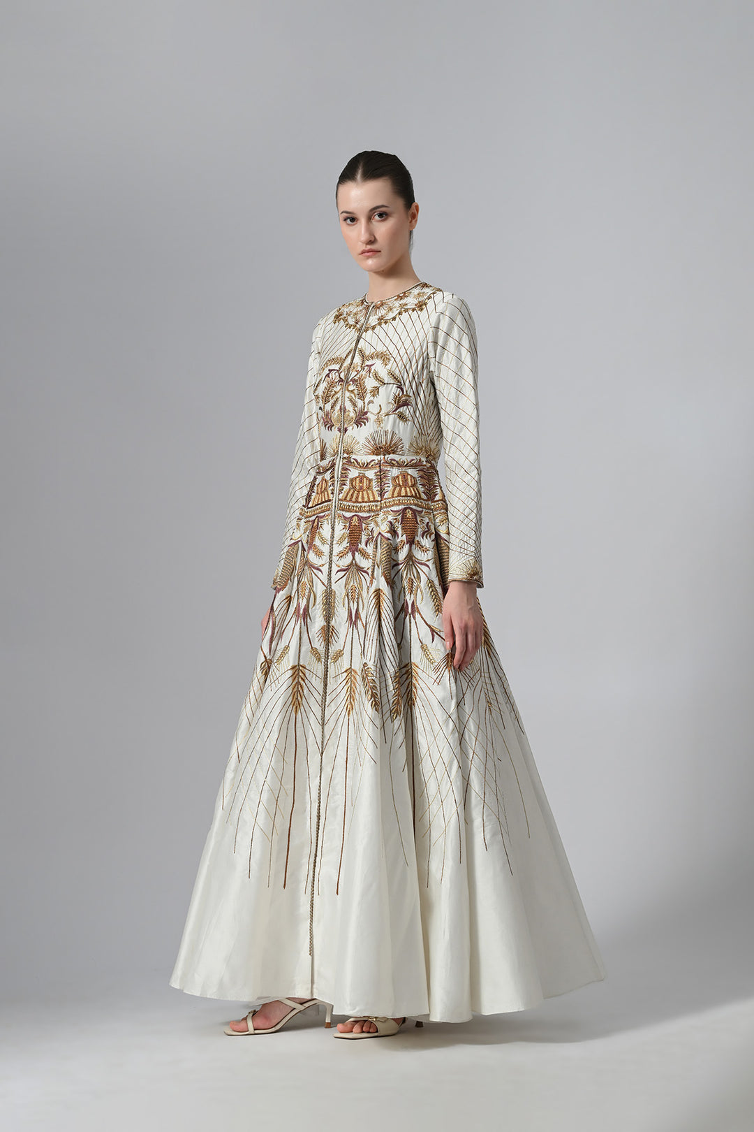 Ivory embroidered A-line gown featuring elegant round neckline, full-sleeves, structured bodice, and the gown is adorned with intricate botanical &amp; heritage-inspired motifs.