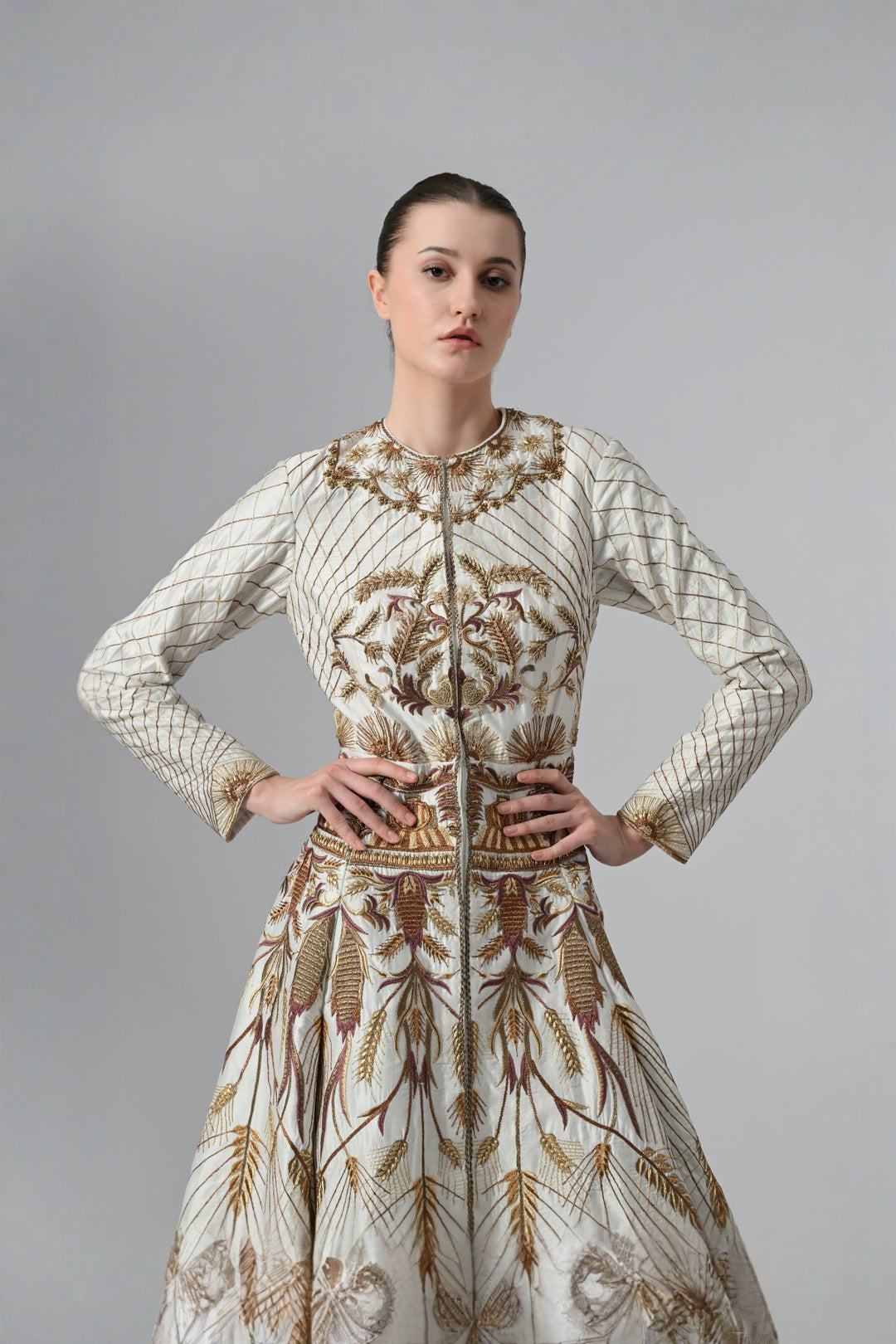 Ivory embroidered A-line gown featuring elegant round neckline, full-sleeves, structured bodice, and the gown is adorned with intricate botanical &amp; heritage-inspired motifs.