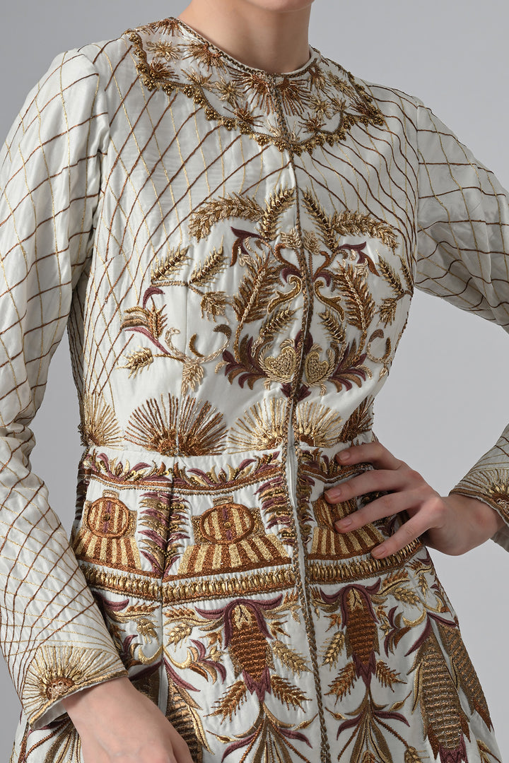 Ivory embroidered A-line gown featuring elegant round neckline, full-sleeves, structured bodice, and the gown is adorned with intricate botanical &amp; heritage-inspired motifs.