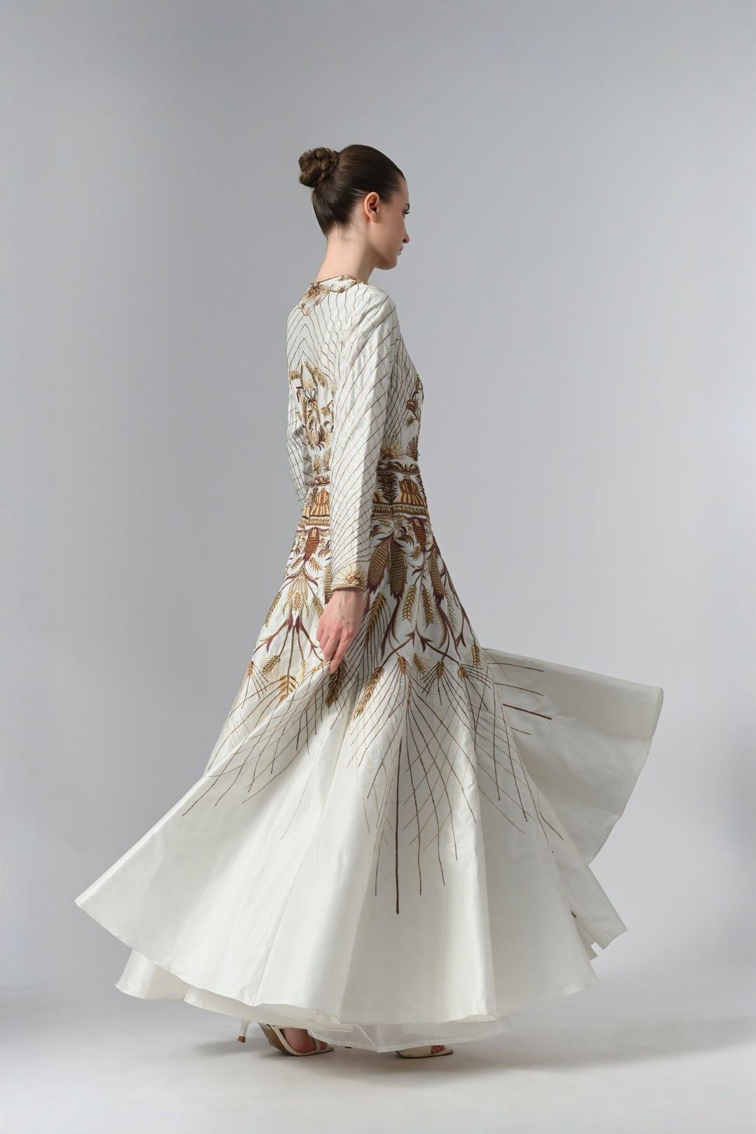 Ivory embroidered A-line gown featuring elegant round neckline, full-sleeves, structured bodice, and the gown is adorned with intricate botanical &amp; heritage-inspired motifs.