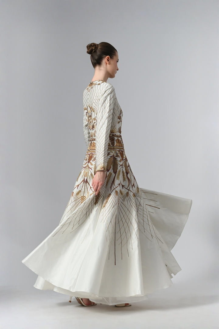 Ivory embroidered A-line gown featuring elegant round neckline, full-sleeves, structured bodice, and the gown is adorned with intricate botanical &amp; heritage-inspired motifs.