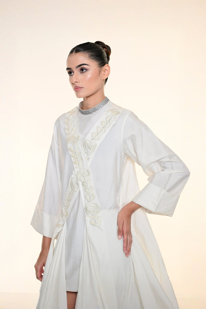 Ivory draped overlay dress with tonal floral embroidery, cascading panels, and relaxed statement sleeves.
