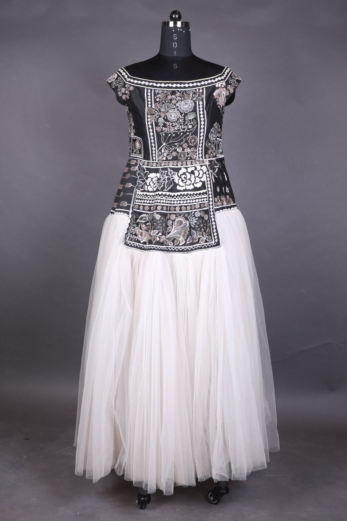 Elegant white dress with intricate black and silver embroidery on a gray background