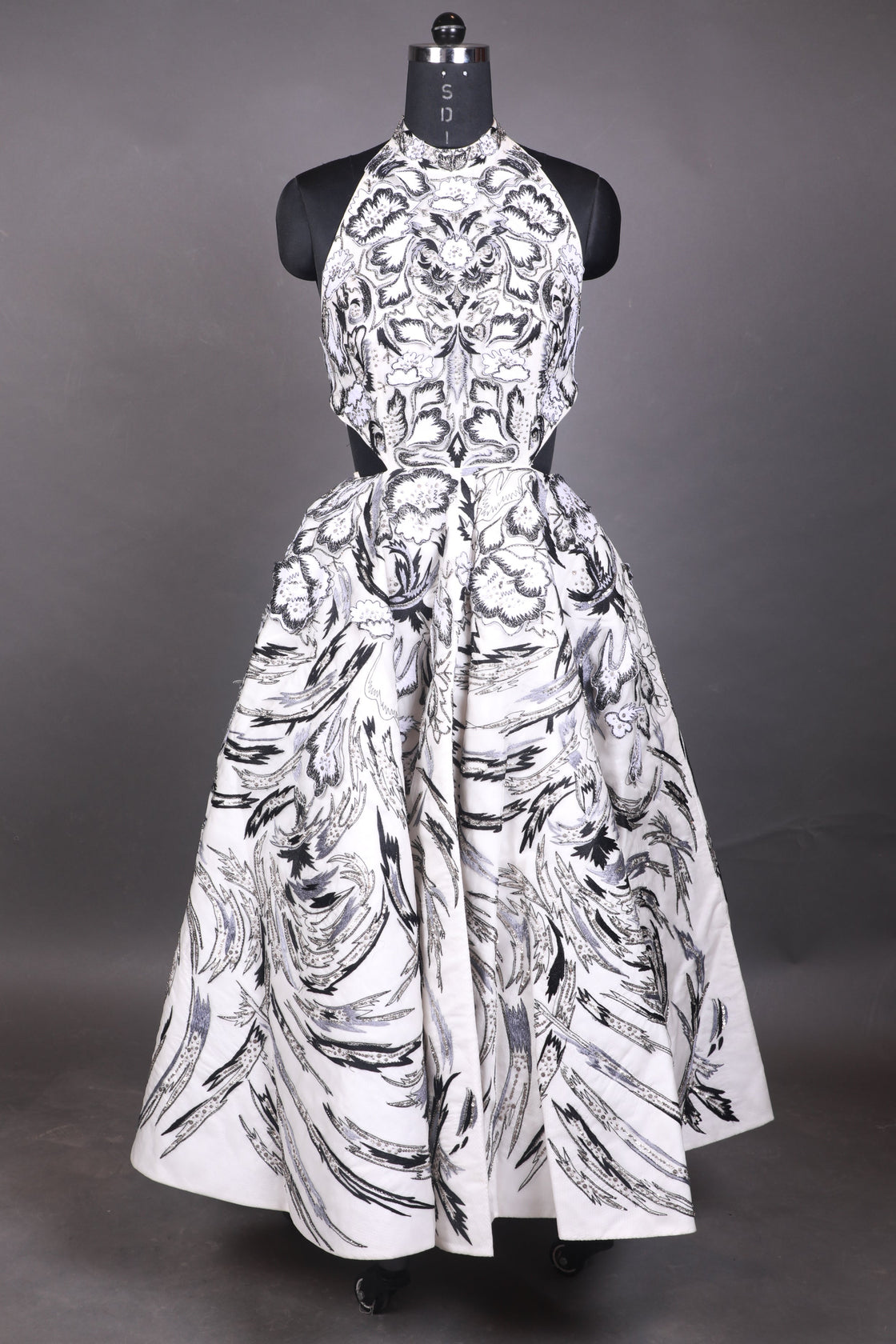 White dress with black pattern on a mannequin against a dark background